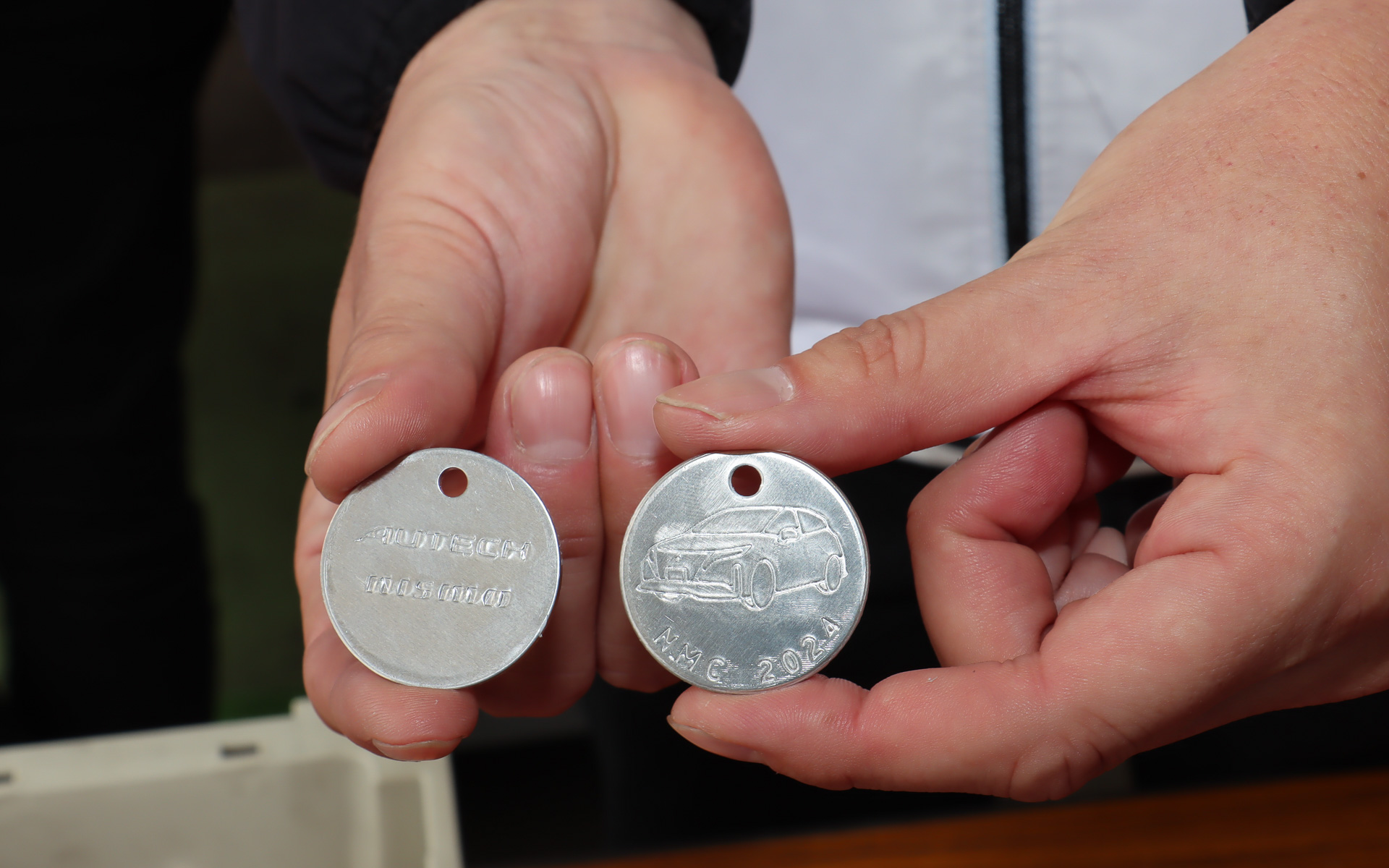 モノづくり体験ブースではイベント参加の記念品にもなるメダル作成を実施。事前に打ち抜かれて片面に刻印したメダルの無地面に油圧プレスでロゴを刻印したあと、紙やすりと研磨剤を使ってピカピカに磨き上げていく