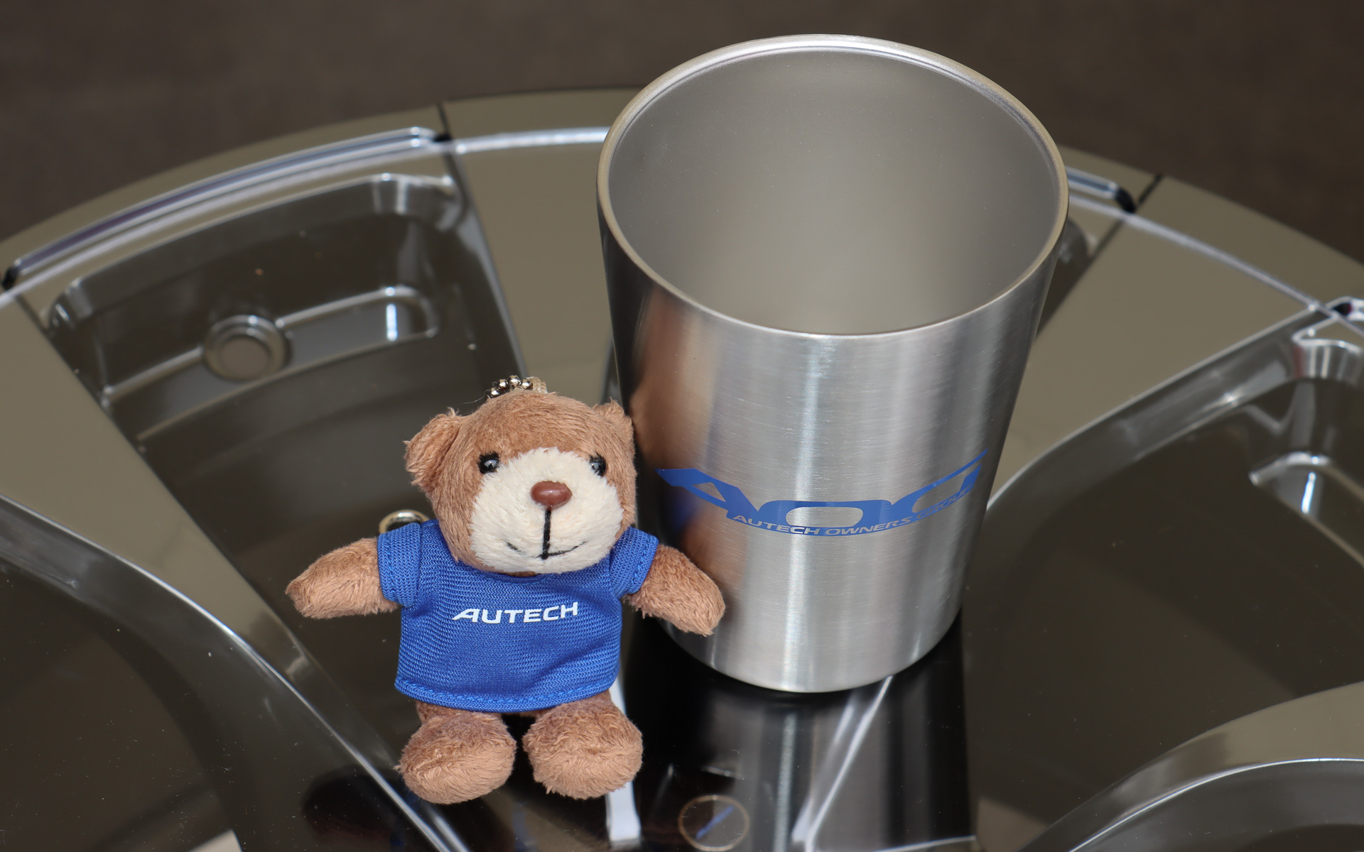 長蛇の列ができたグッズ販売ブースでは、会場限定アイテムとしてオーテックのロゴ入りシャツを着用したベアマスコットとAOGのロゴ入りタンブラーを販売した