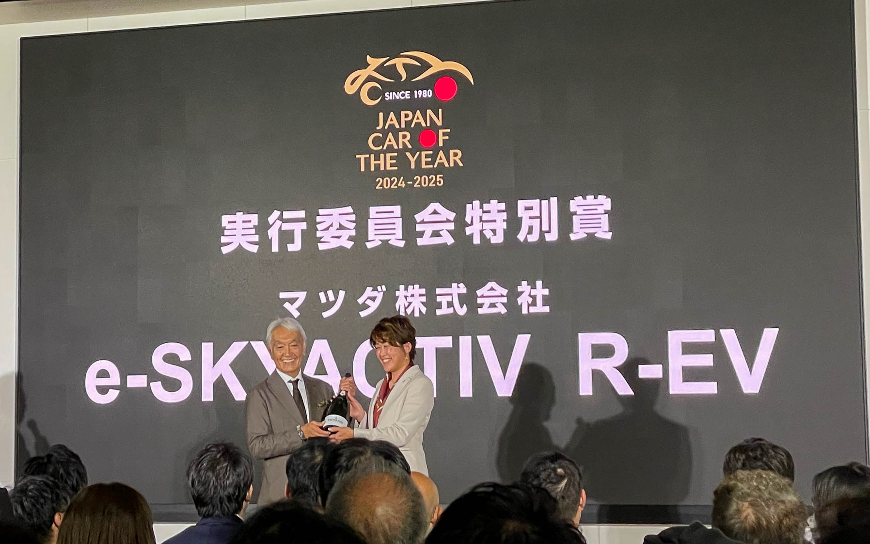 実行委員会特別賞はマツダのe-SKYACTIV R-EV。ロータリーエンジンを発電機としたレンジエクステンダーを加えたMX-30の主査、岡留さんがFERRARIのスパークリングワインを受け取った