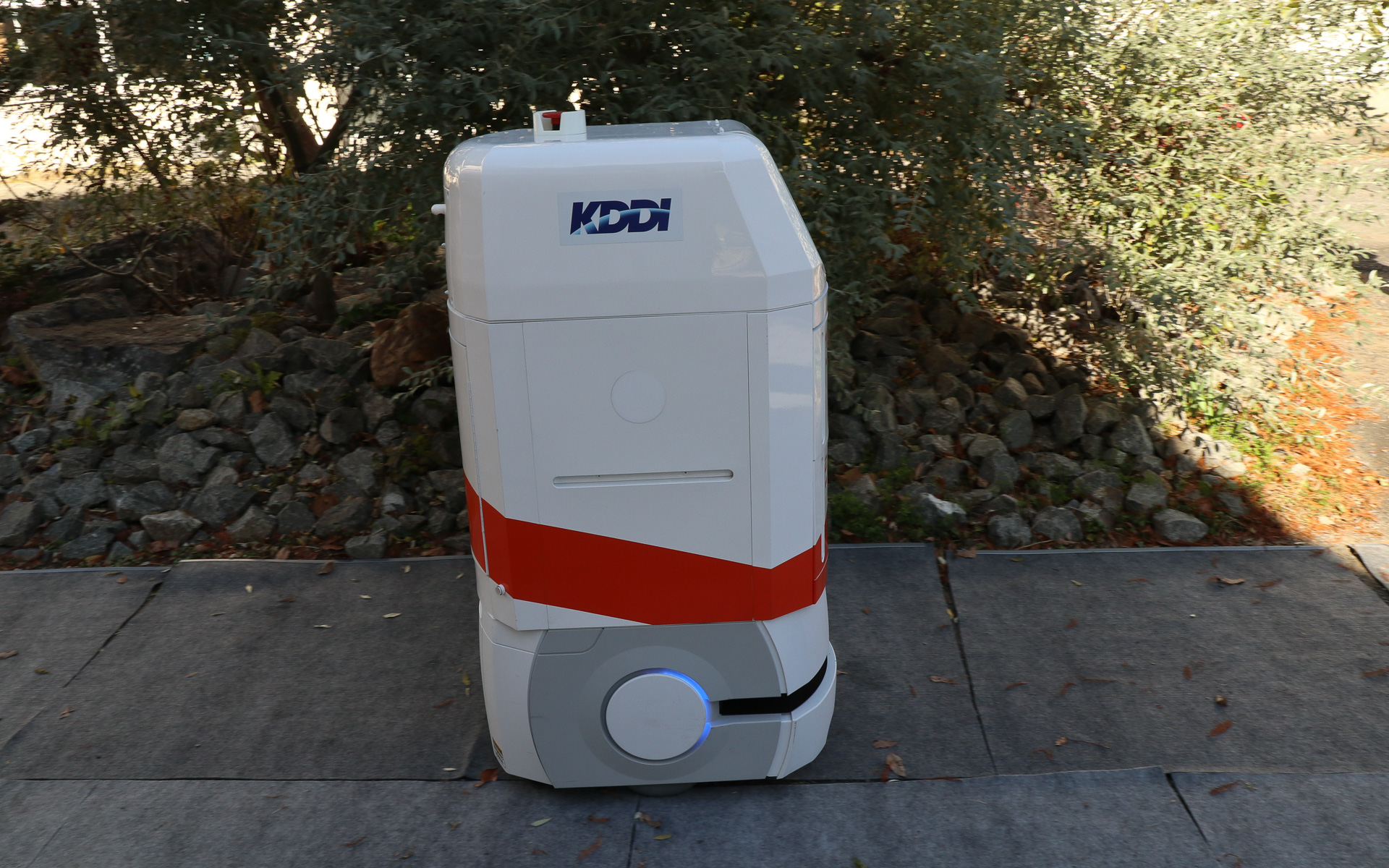 配送ロボットのスタートと連動して自動運転車が校門前のロータリーに走ってきて、どちらかが待つことなく同タイミングで合流