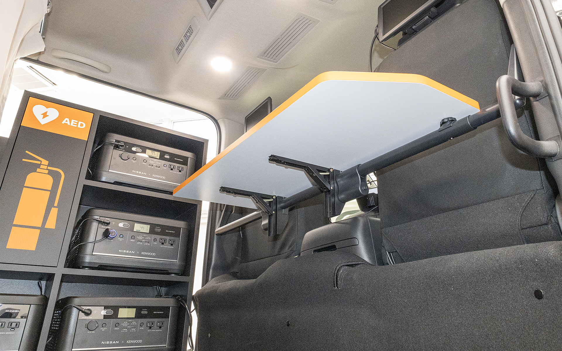 デスクはパーテーションパイプを利用して折りたたみ式としている。電源はポータブルバッテリから取る。事務スペースの照明は純正アクセサリーのワークランプで2個使用