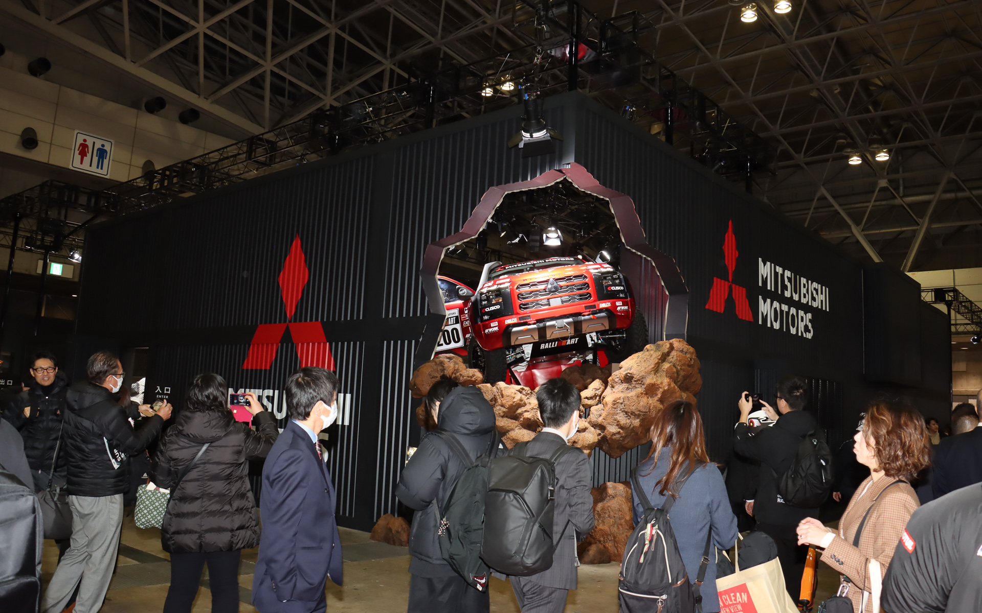 「トライトン」のラリーマシンが壁を突き破ったようなデザインでも「カッコよく遊び尽くせ！」というテーマを表現する三菱自動車ブース。多くの人が注目して足を止め、写真撮影してから中に入っていった