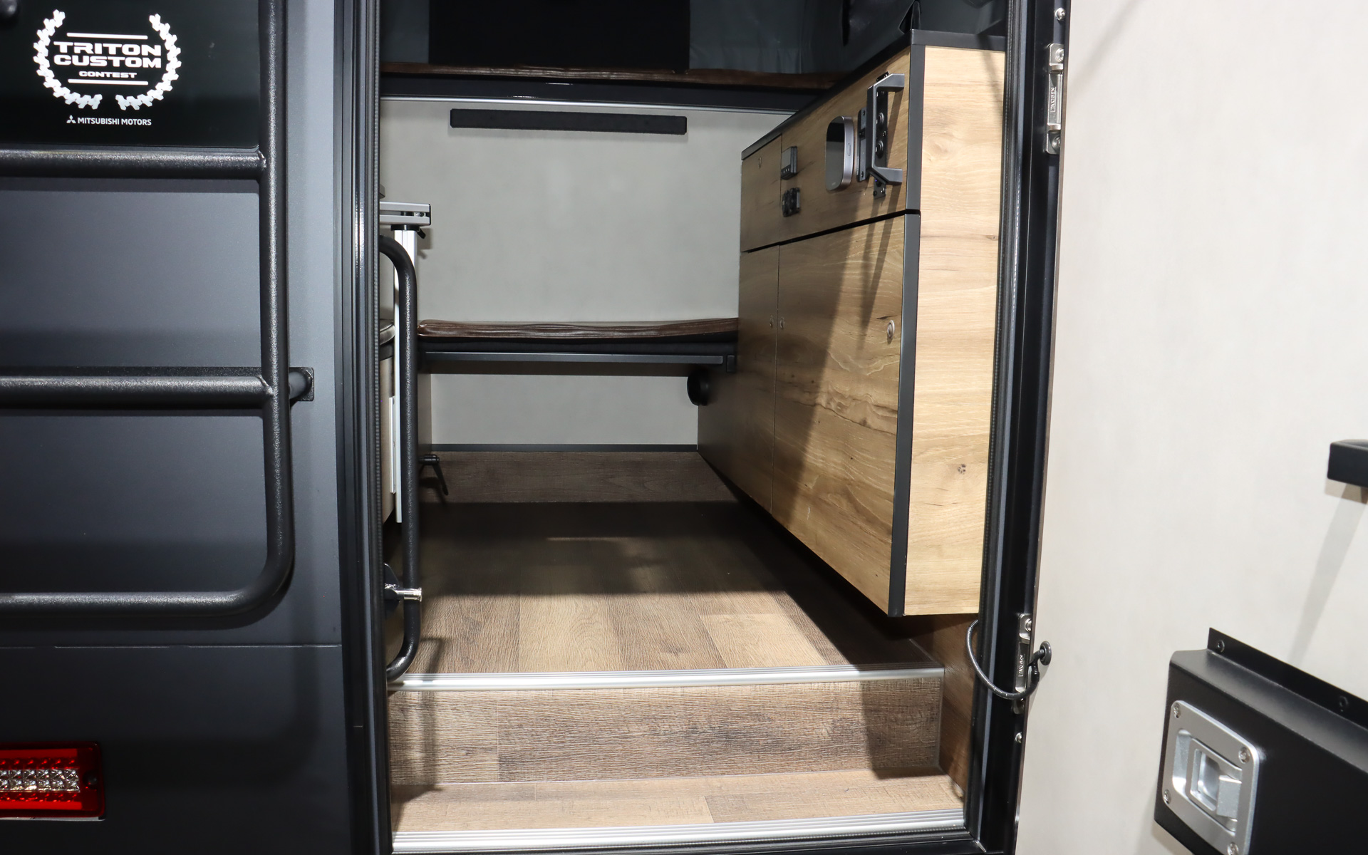 車両後方に冷蔵庫付きの本格的なキッチン、テーブル、エアコンなどを完備