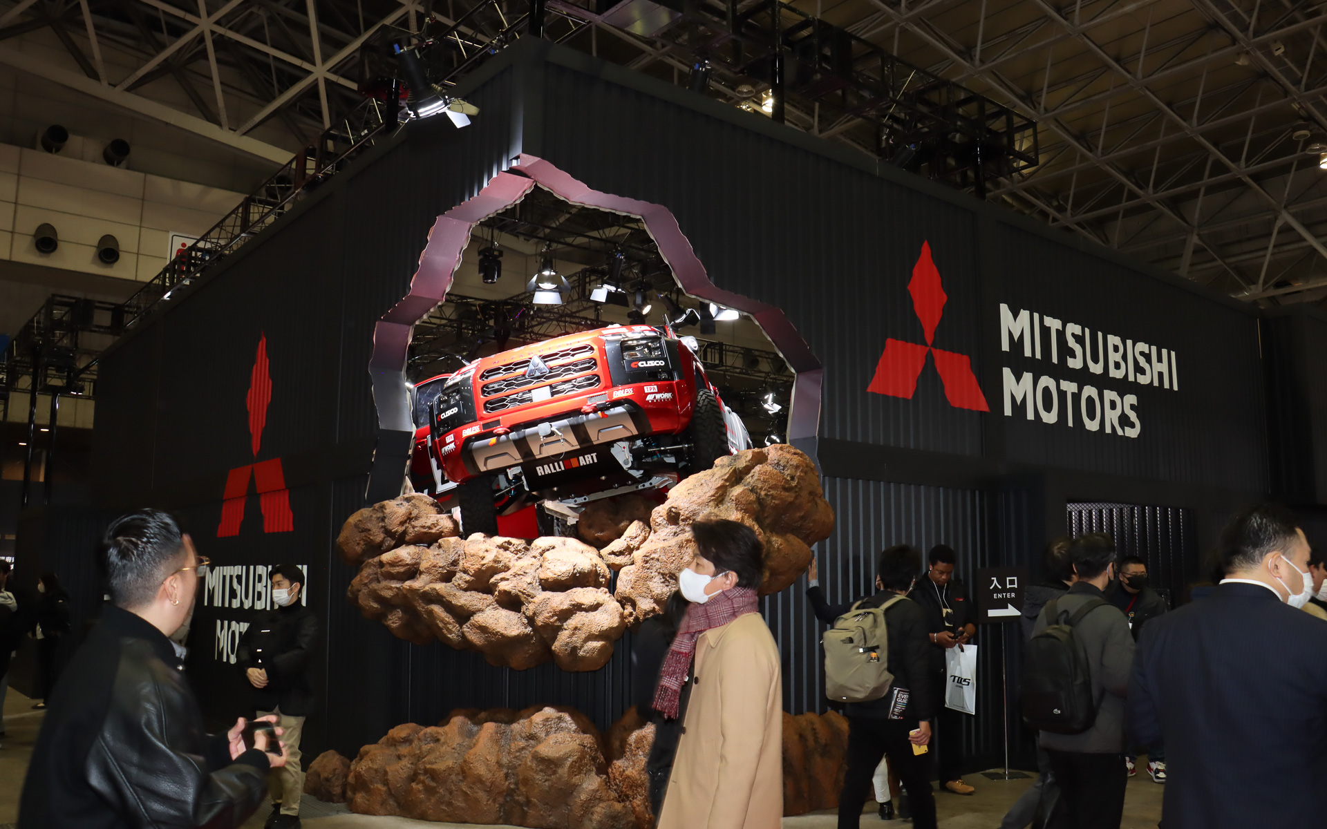 まるでトライトン AXCR 2024 ラリーカーが壁を突き破って飛び出そうとしているような斬新なスタイルで車両展示