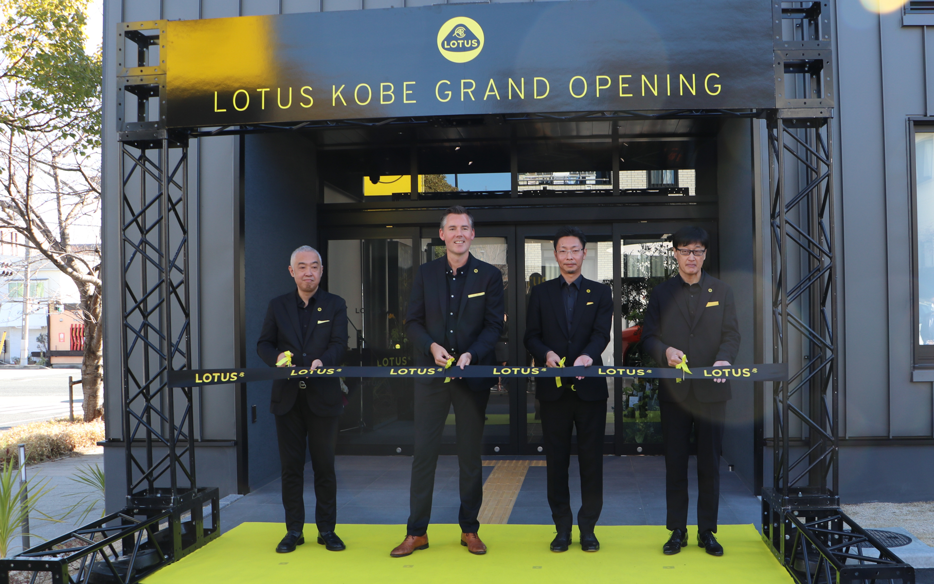 店舗入り口前にて記念のテープカットを実施。左からロータスカーズ ヘッド of オペレーション 日本＆台湾担当 寺嶋正一氏、英ロータス カーズ ヨーロッパ アジアパシフィック ミドルイースト＆アフリカ プレジデント＆CEOのダン・バルマー氏、株式会社ジースクエア仙台 代表取締役 大滝歩氏、株式会社ジースクエア仙台 代表取締役 宮本輝夫氏