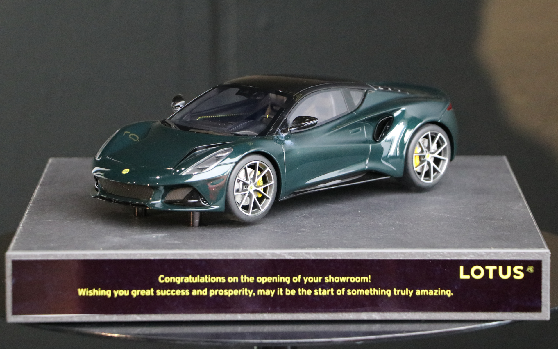 ロータス神戸のオープンを記念して、英ロータスから「エミーラ」のダイキャストカーが贈呈された。台座には開店祝いと商売繁盛の激励コメントが刻まれている