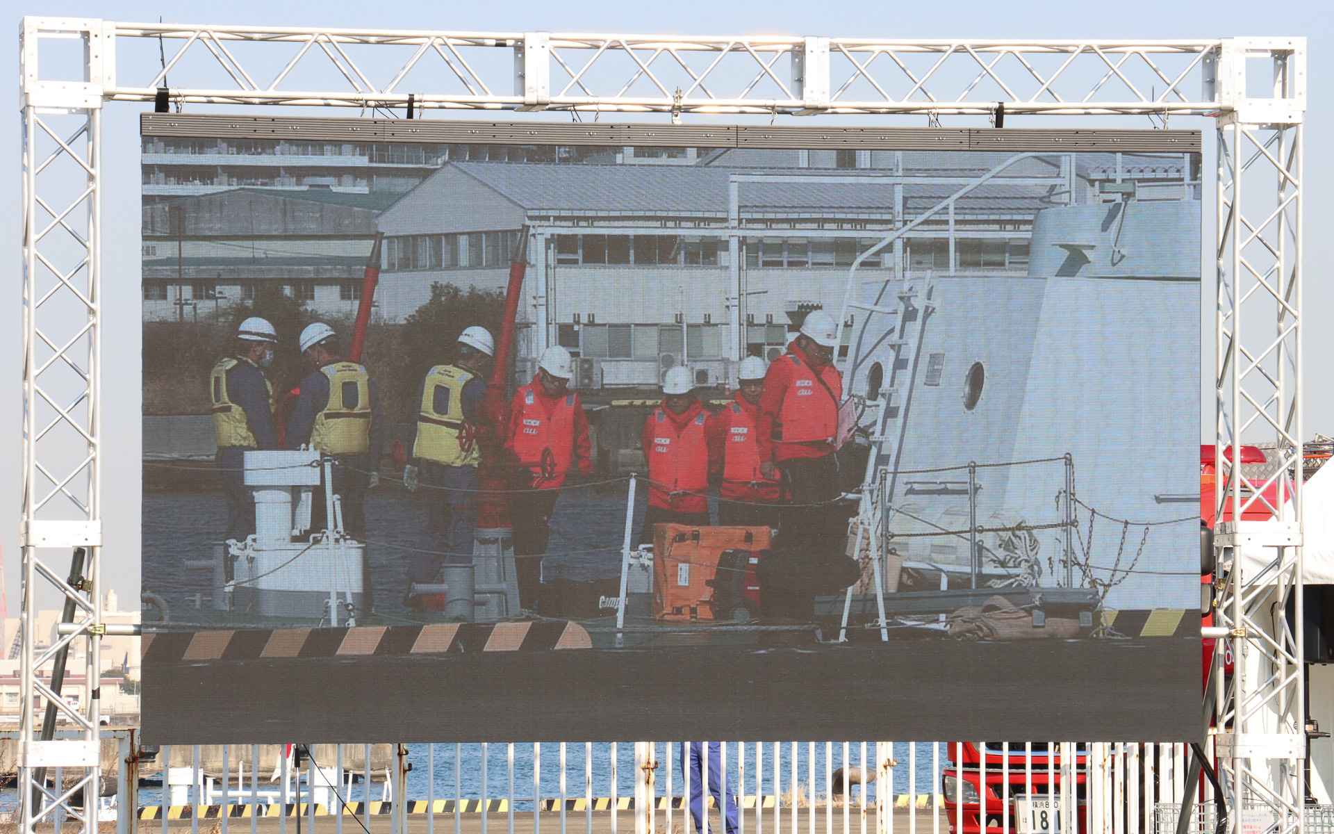 海上保安庁の巡視艇「はまなみ」からKDDI 現地復旧班が下船し、海上保安庁の職員からStarlink復旧機材を受領。雨や海水の影響で浸水被害が出ないよう、各機材は防水カバーで覆われている