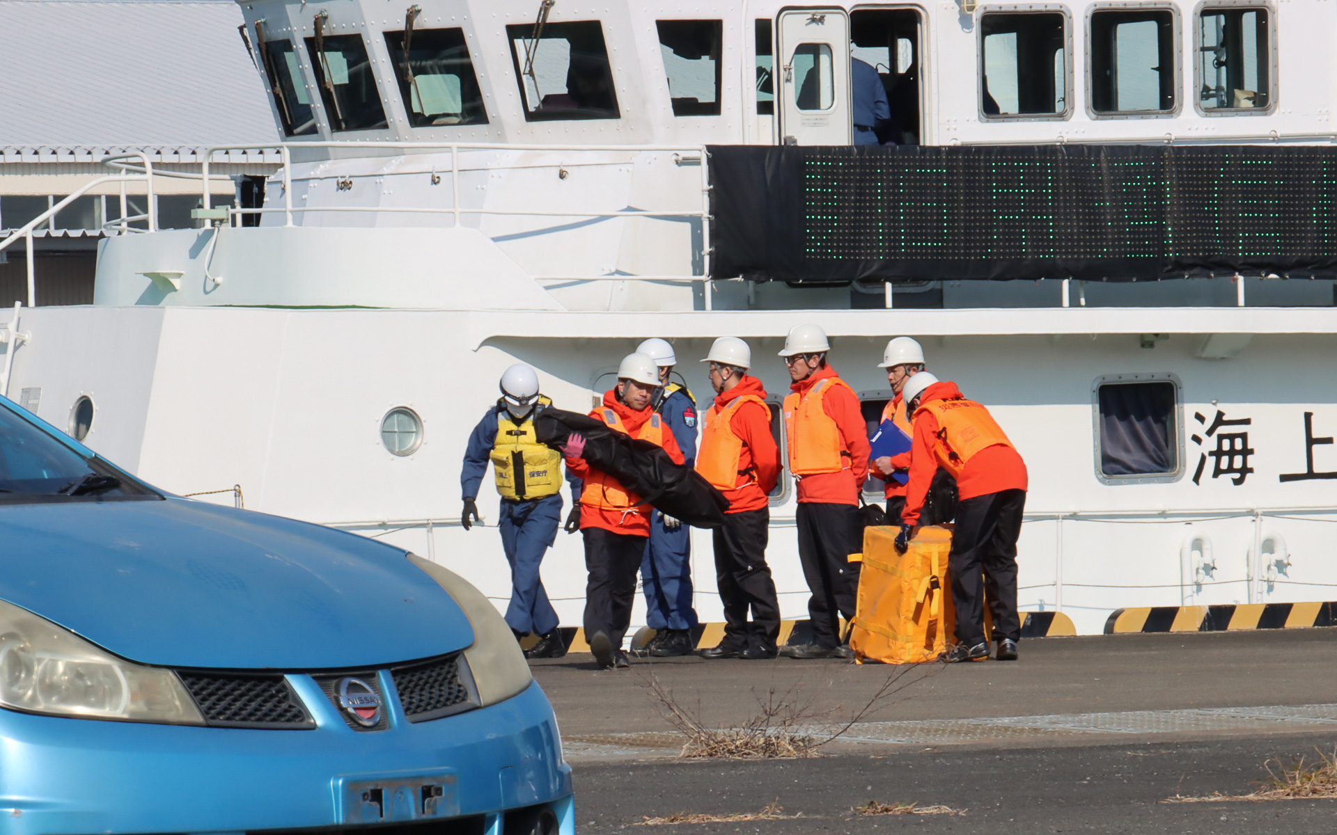 海上保安庁の巡視艇「はまなみ」からKDDI 現地復旧班が下船し、海上保安庁の職員からStarlink復旧機材を受領。雨や海水の影響で浸水被害が出ないよう、各機材は防水カバーで覆われている