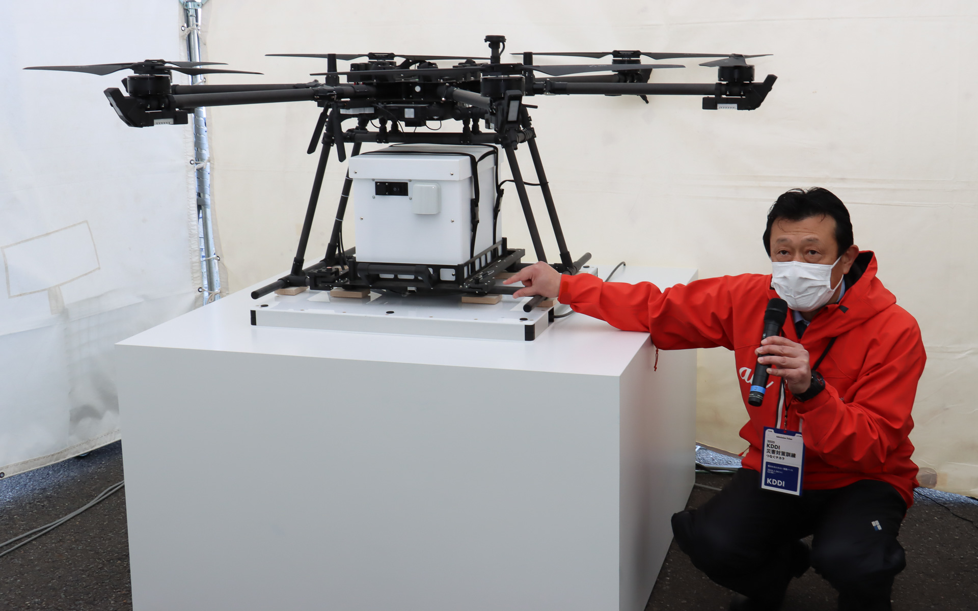 ドローンから吊り下げられた白いボックス内にある蓄電池から、OPSにケーブル接続されたワイヤレス給電ベースに電力が送られ、基地局機能を維持する実証も行なわれる予定とのこと