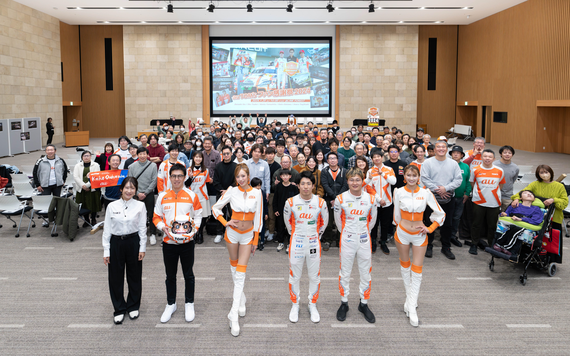 左から司会の今井優杏さん、伊藤大輔監督、auサーキットクイーンの央川かこさん、坪井翔選手、山下健太選手、辻門アネラさんと大勢の参加者と記念撮影