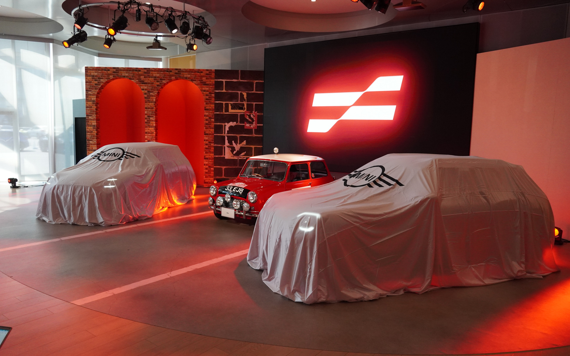 MINI JOHN COOPER WORKS EとMINI JOHN COOPER WORKS ACEMAN Eをベールに包んだ状態で発表会がスタート。中央にはクラシックMINIのモンテカルロラリー仕様車