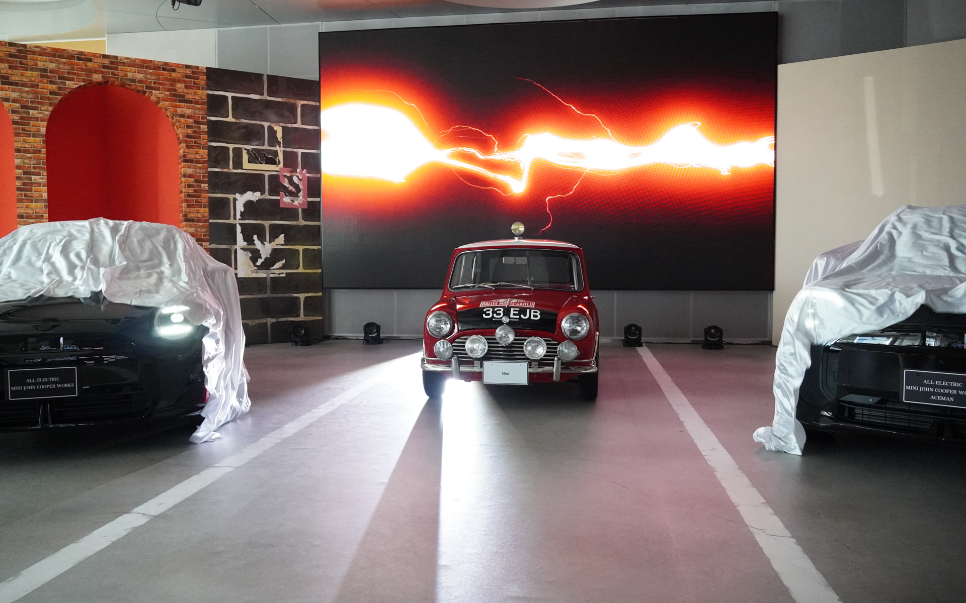 MINI JOHN COOPER WORKS EとMINI JOHN COOPER WORKS ACEMAN Eをベールに包んだ状態で発表会がスタート。中央にはクラシックMINIのモンテカルロラリー仕様車