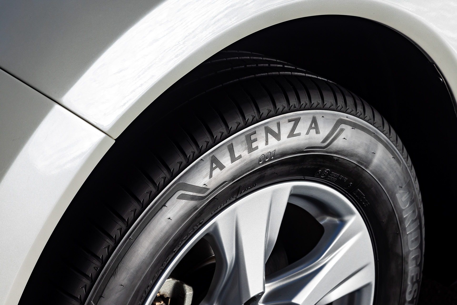 <a href="https://tire.bridgestone.co.jp/alenza/?utm_source=CarWatch&utm_medium=tieup&utm_campaign=alenza2025" class="n" target="_blank">アレンザ 001</a>ではタイヤ骨格部分を重構造とすることで高剛性を保ち、高いドライ性能を実現。パターンではリブ端部の角の丸めを最適化してリブ中央の接地圧を高める「マルチラウンドブロック」を採用し、ウェットグリップ性能を向上。また、ブロック端の角を丸めることで制動時におけるエッジの巻き込み変形を制御し、制動時のフラットな接地を実現する「チャンファリング」技術を採用したほか、低燃費性能とライフ性能の向上を目的に「ナノプロ・テック」を採用したシリカ配合によってシリカ同士の擦れ合いによる発熱を低減。ライフ性能を落とすことなく、転がり抵抗を低減することに成功したという
