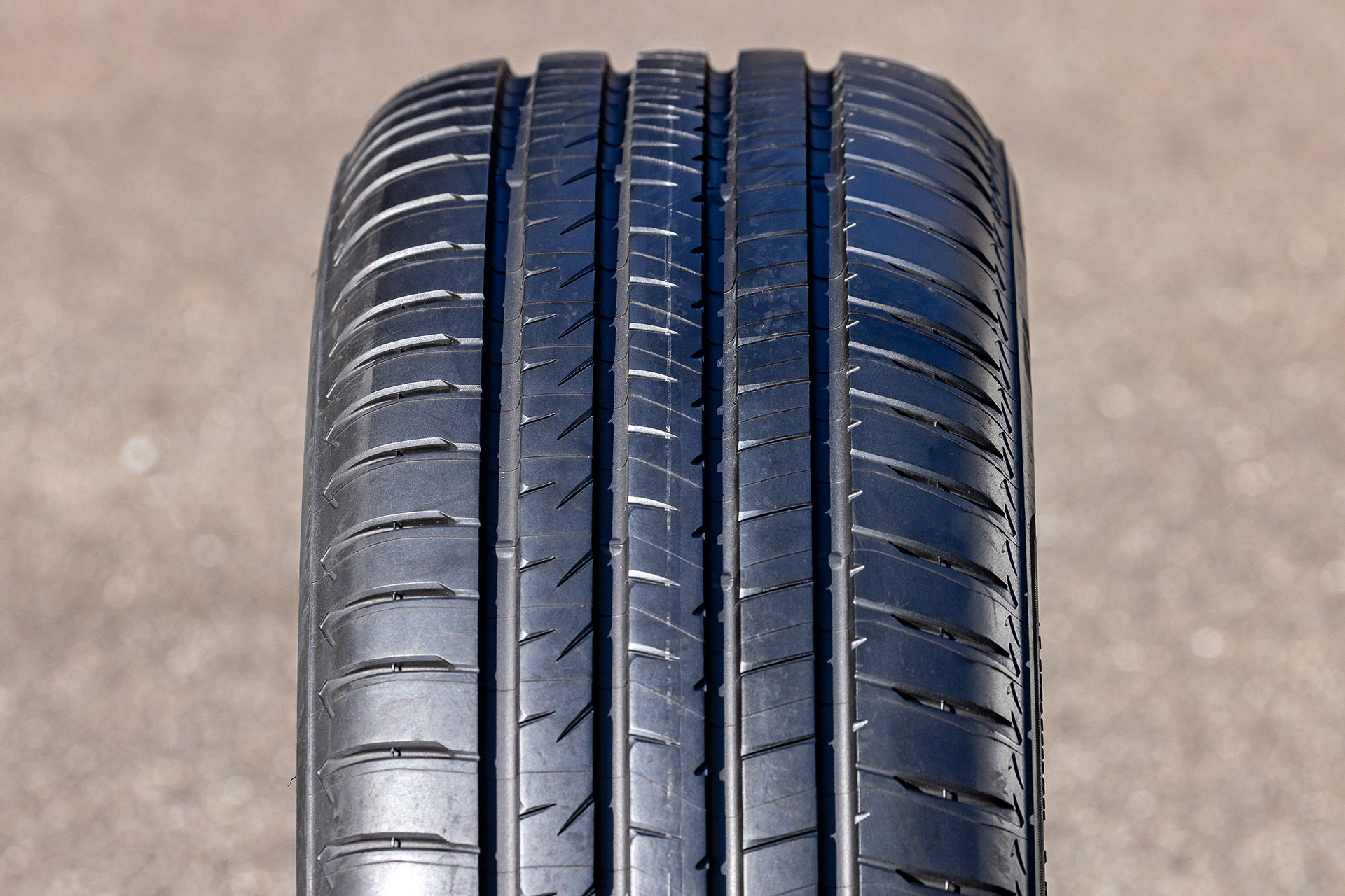 <a href="https://tire.bridgestone.co.jp/alenza/?utm_source=CarWatch&utm_medium=tieup&utm_campaign=alenza2025" class="n" target="_blank">アレンザ 001</a>ではタイヤ骨格部分を重構造とすることで高剛性を保ち、高いドライ性能を実現。パターンではリブ端部の角の丸めを最適化してリブ中央の接地圧を高める「マルチラウンドブロック」を採用し、ウェットグリップ性能を向上。また、ブロック端の角を丸めることで制動時におけるエッジの巻き込み変形を制御し、制動時のフラットな接地を実現する「チャンファリング」技術を採用したほか、低燃費性能とライフ性能の向上を目的に「ナノプロ・テック」を採用したシリカ配合によってシリカ同士の擦れ合いによる発熱を低減。ライフ性能を落とすことなく、転がり抵抗を低減することに成功したという