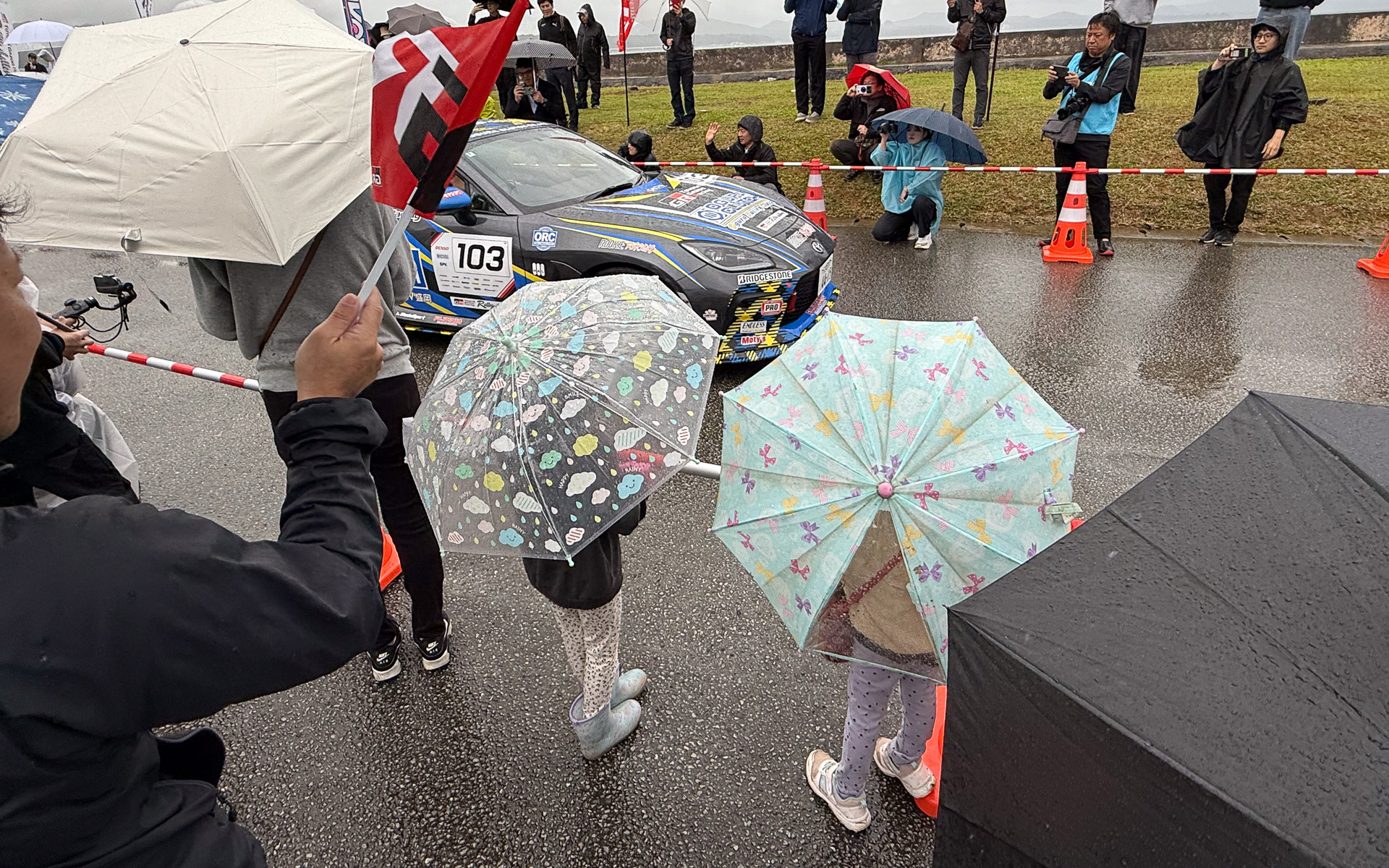総合優勝した103号車 佐々木雅弘/小紫知慧組のGR86（小倉クラッチ BS GR86-MASA）のスタート風景。ラリチャレ沖縄では、雨という天候にもかかわらず多くの家族連れを見ることができた