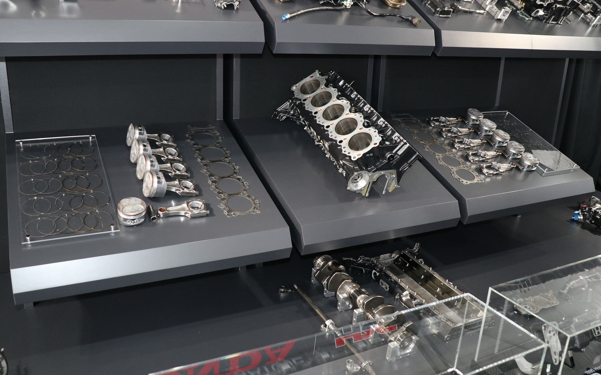 販売されるホンダ RA100Eの全点展示。オークションでは台座ごとの単位でセット販売される予定。分解に際してエンジンオイルやサビなどの汚れは除去されたが、燃焼で発生したススなどはできる限り残され、レースヘリテージを現代に伝える貴重なアイテムとなっている