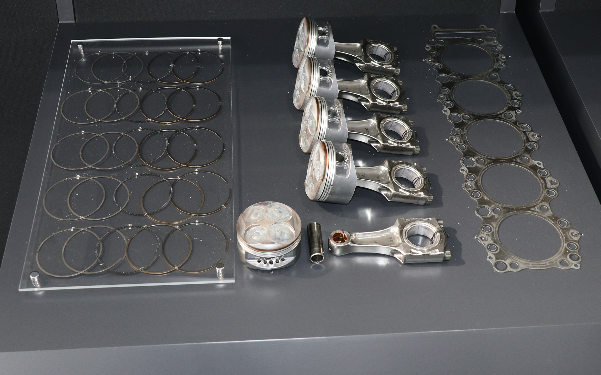 販売されるホンダ RA100Eの全点展示。オークションでは台座ごとの単位でセット販売される予定。分解に際してエンジンオイルやサビなどの汚れは除去されたが、燃焼で発生したススなどはできる限り残され、レースヘリテージを現代に伝える貴重なアイテムとなっている