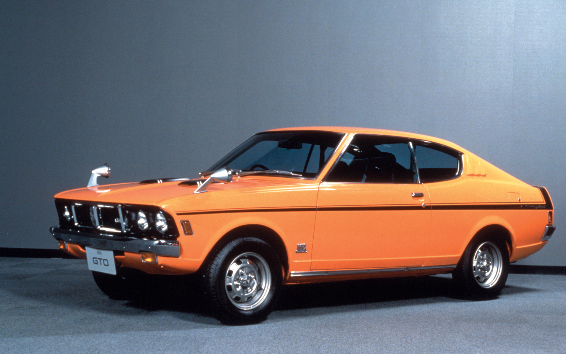 「ギャランGTO MR」。1970年に発売した2ドアハードトップクーペで、ファストバックスタイルとダックテールデザインが特徴。1.6リッターDOHCエンジンを搭載し、黒を基調とした航空機の操縦席をイメージした革新的な内装デザインで操作性が高く、運転席まわりには8連メーターが配置されるなど豊富な計器類が特徴