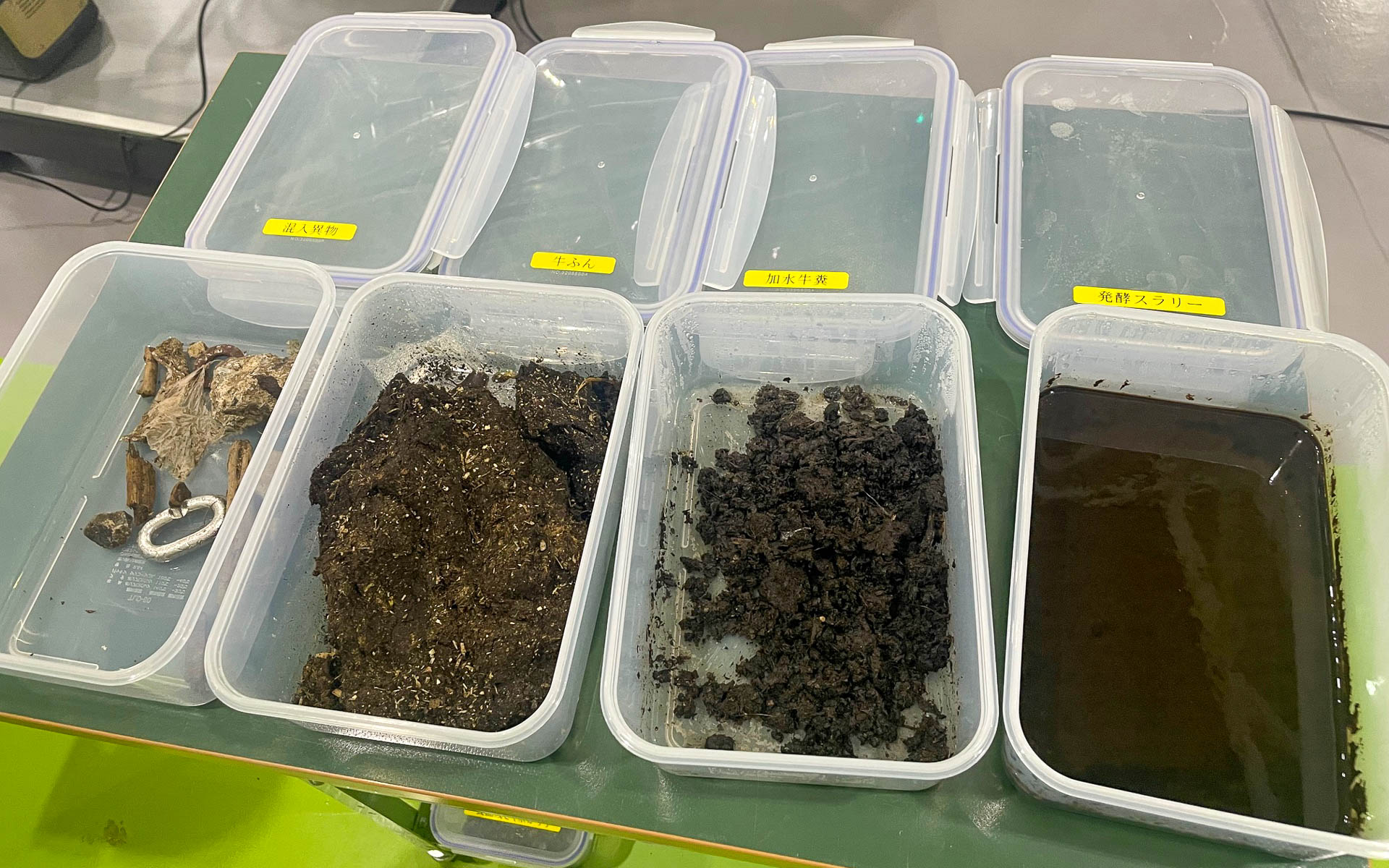 実証プラントのサンプル。一番左は搬入されてくる牛糞などに混じっていた異物。右は発酵スラリー（粘性の強い液体）