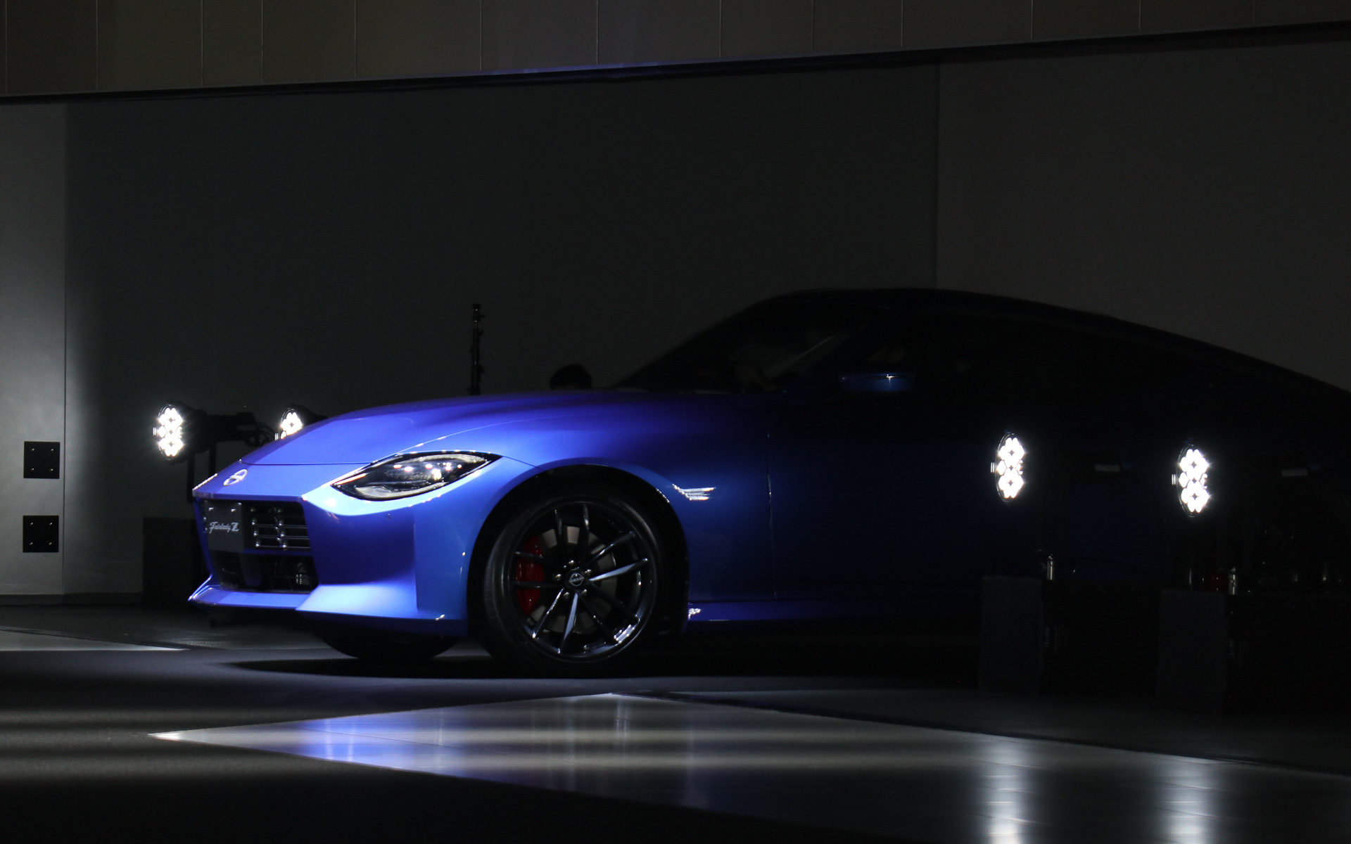 日産ホール側のシャッターが開いて「ワンガンブルー」の「フェアレディZ」が登場。ステアリングを握る鈴木さんはそのままゆっくりとフェアレディZを走らせ、日産グローバル本社ギャラリーのステージ上に上がった