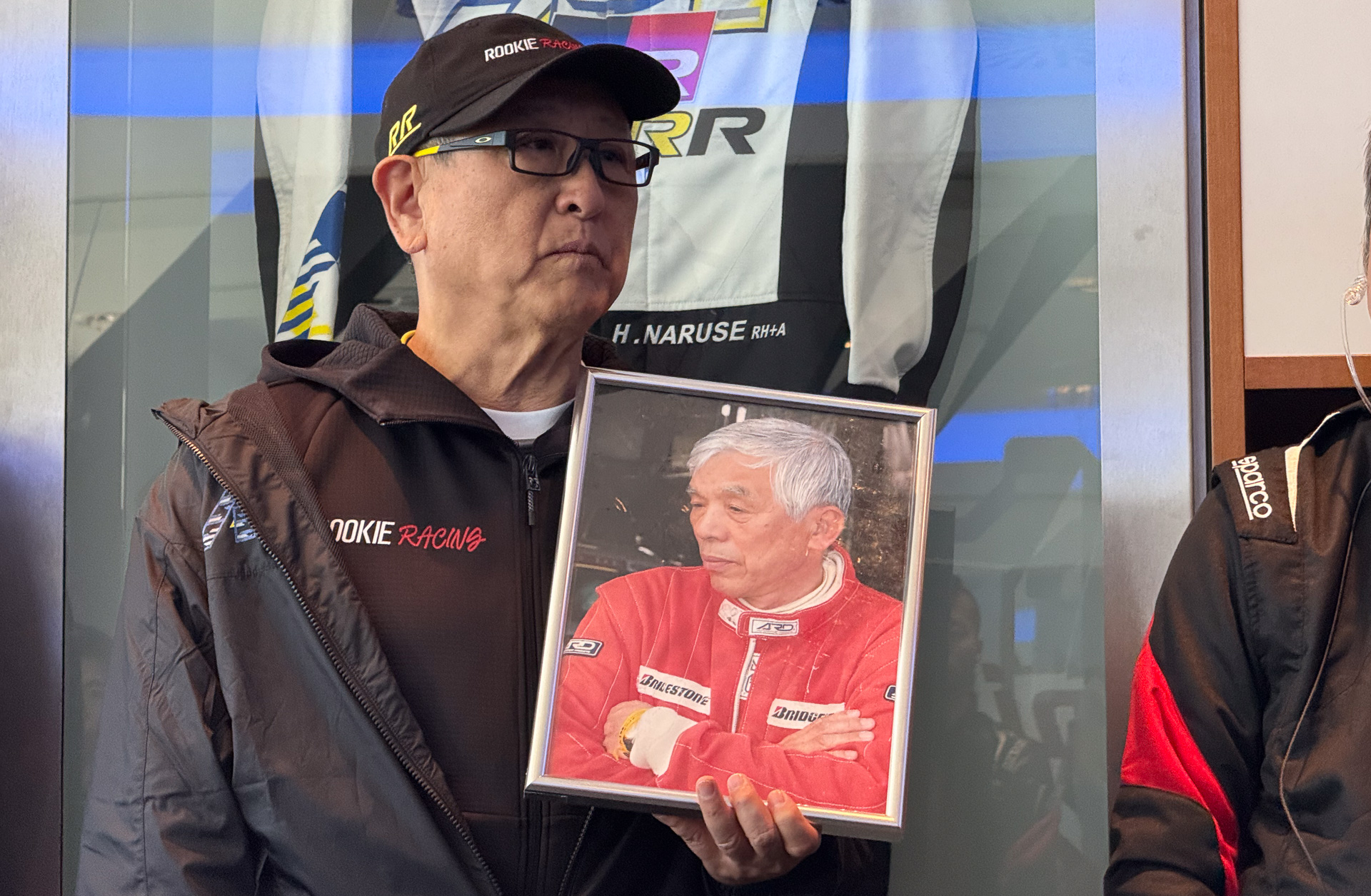 成瀬弘氏とともに戦う決意を語るトヨタ自動車株式会社 代表取締役会長 豊田章男氏。GRヤリス、GRスープラの2台完走後、チームのみんなに思いを伝えた。後方は、成瀬氏のために用意したレーシングスーツ