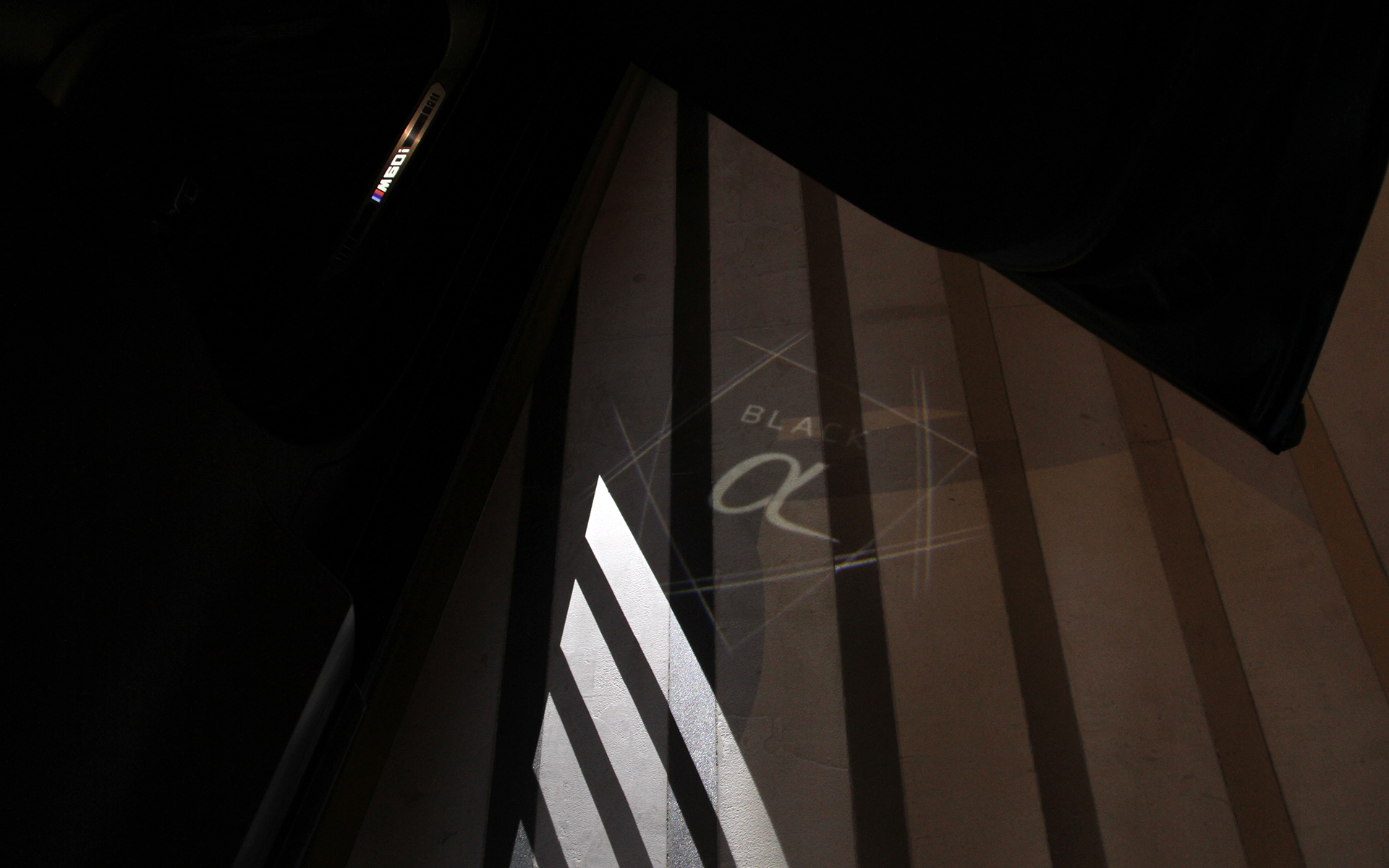 ひと筆の線で描いた「α」が輝く姿を表現したドアプロジェクター