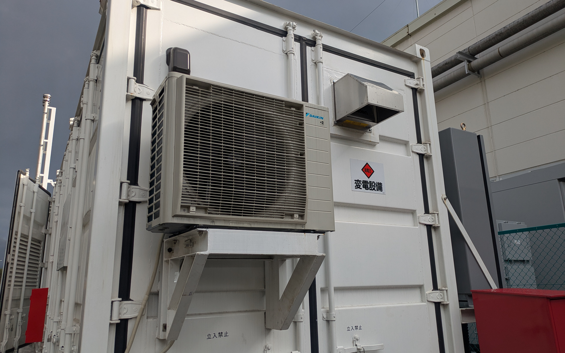 コンテナ内の制御機器を冷却するために内部にはエアコンが設けられ、側面には室外機が設置されている