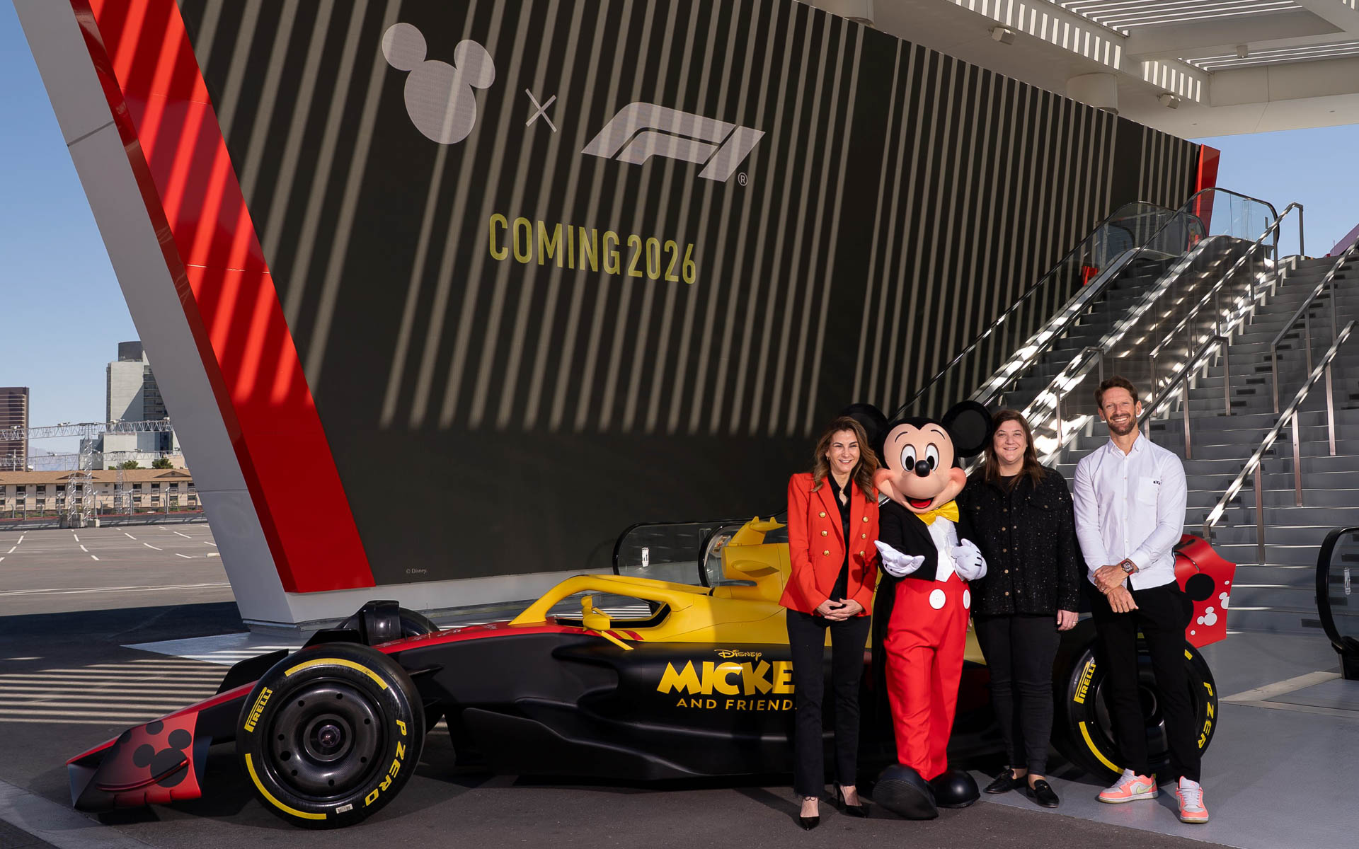 左からディズニー・コンシューマー・プロダクツ社長 テイジア・フィリッパトス氏、ミッキーマウス、フォーミュラ1 チーフ・コマーシャル・オフィサー エミリー・プラツァー氏、ロマン・グロージャン選手