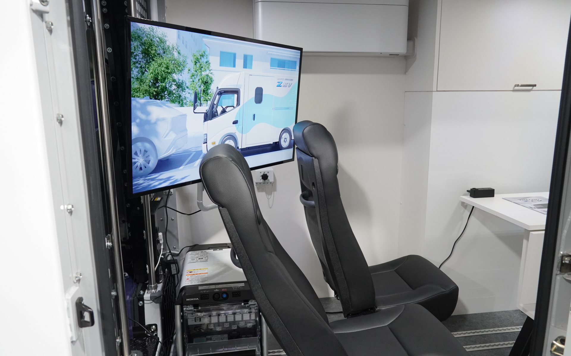 室内には固定された椅子と机、そして壁に一般的なルームエアコンがある