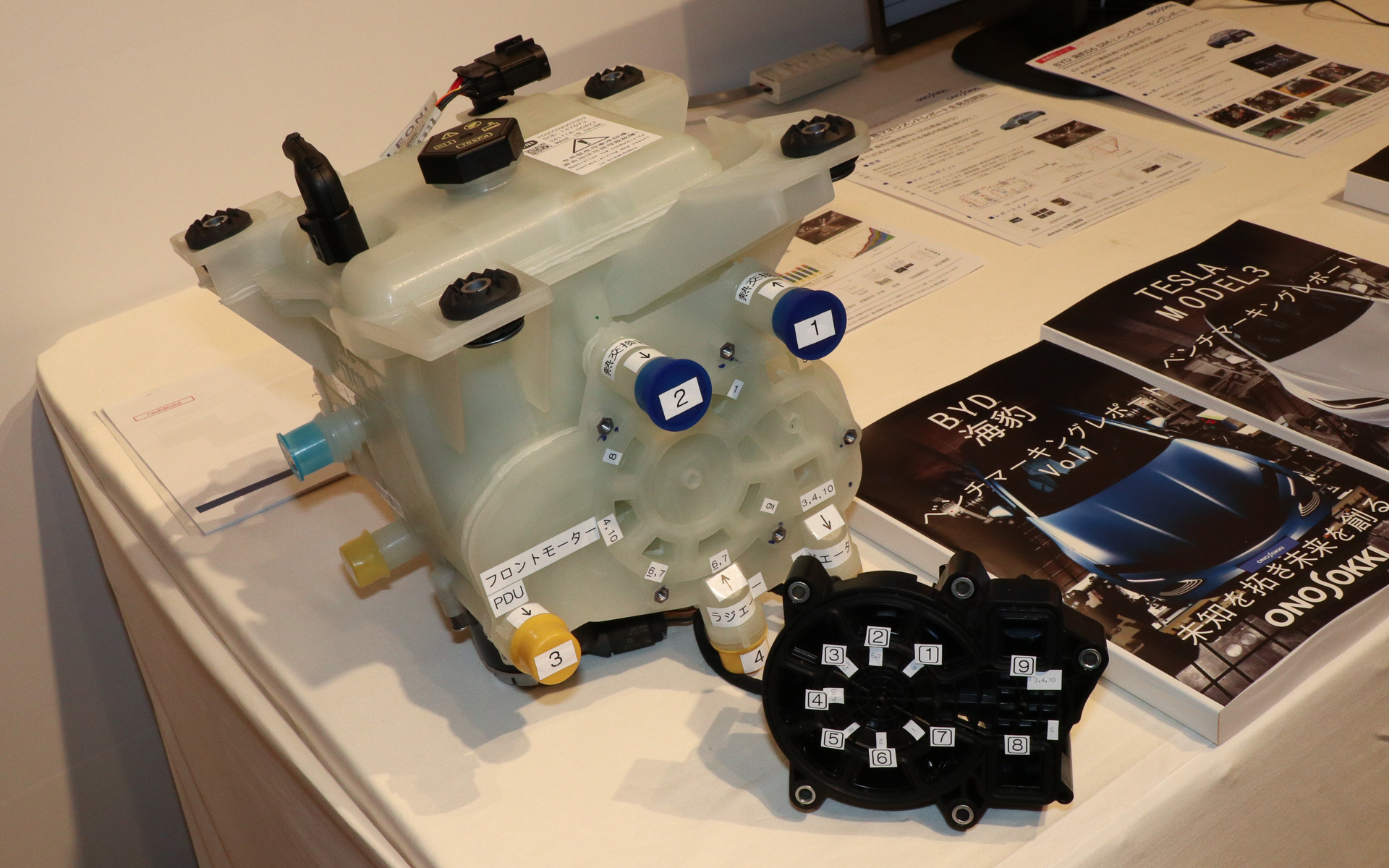 解析用に入手したSU7 Maxのリザーバータンクとバルブ切り替えユニット。本来は組み合わされているが、LLCが流れる経路がどのように対応しているか調べるために取り外し、番号を振ったシールを貼り付けて解析を行なった