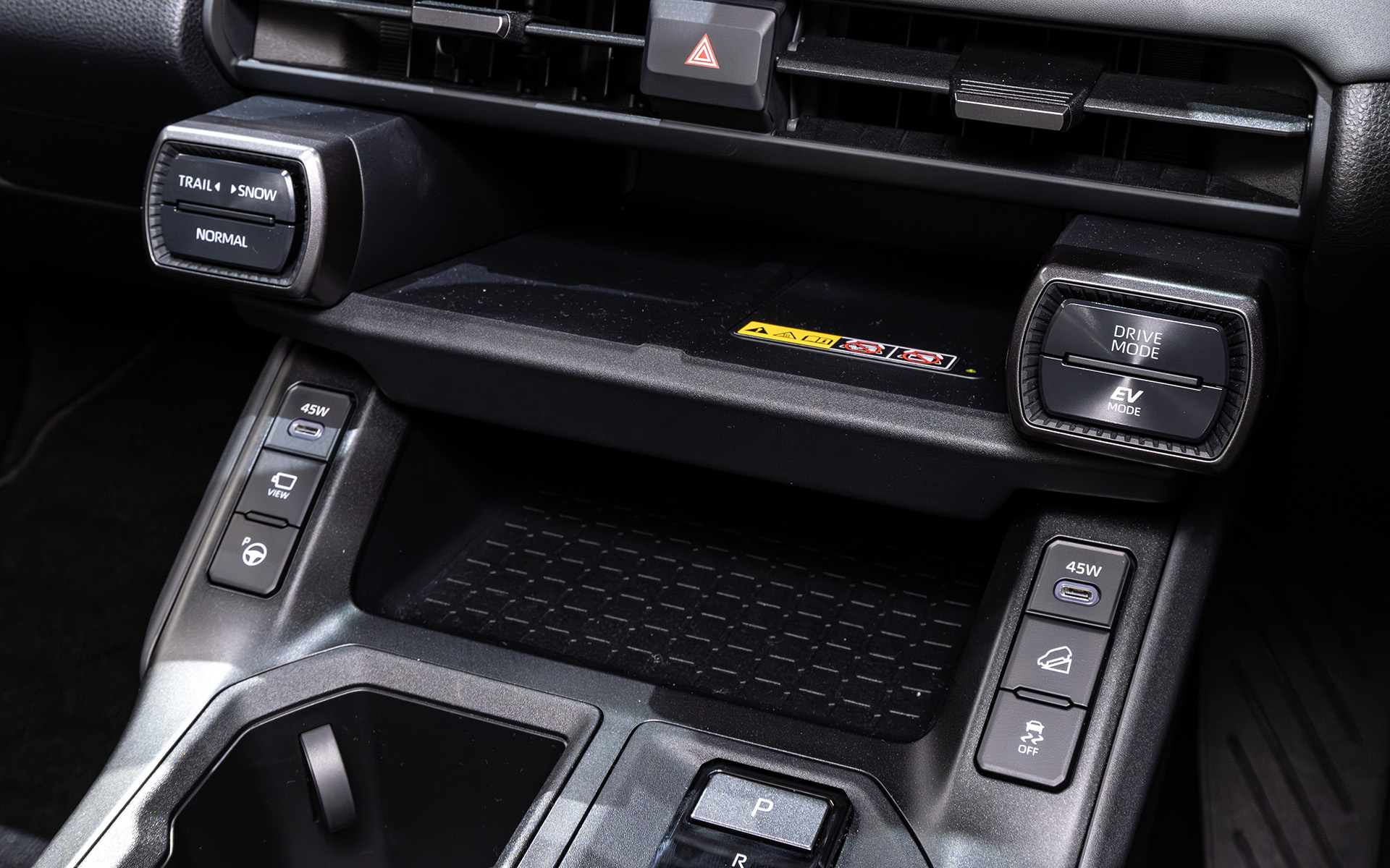 エアコン吹き出し口下は中央がワイヤレス充電を備えたスマホ置き場、左右にドライブモードの切り替えスイッチなどが並ぶ。その下段は小物入れとUSB端子など。ヒルディセントやオートパーキングらしきボタンもある
