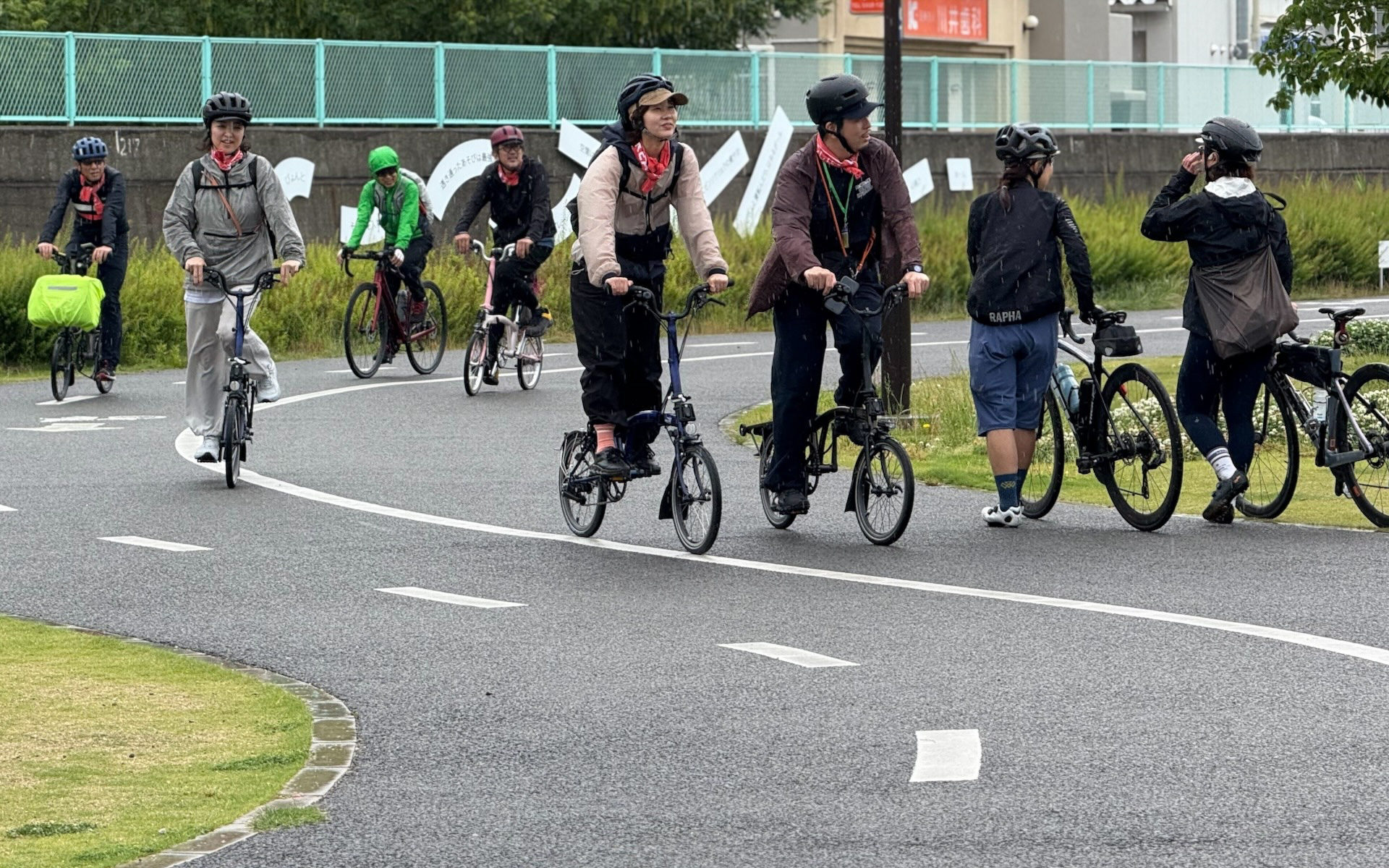 ミャクミャクのモニュメントが置かれていた此花区の正蓮寺川公園付近を通過するブロンプトンの車列。雨が降り始めたが、参加者は楽しそう