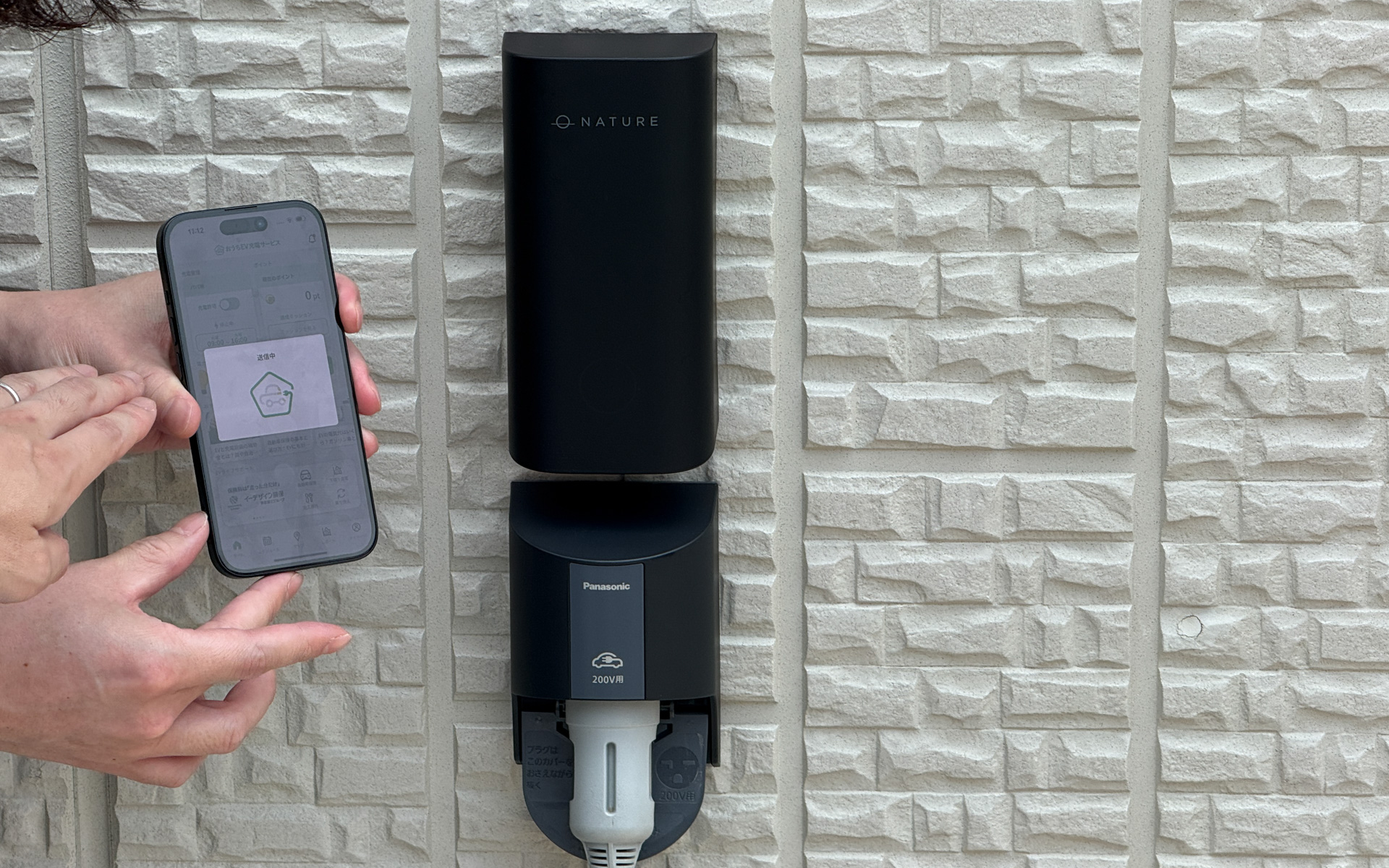 パナソニックの「200V-EVコンセント」の上部に設置された「IoT制御モジュール」。住宅の外壁になじむデザインが採用され、ステータスランプで状態を表示できるほか、LTE内蔵により自宅のWi-Fi連携を不要にした