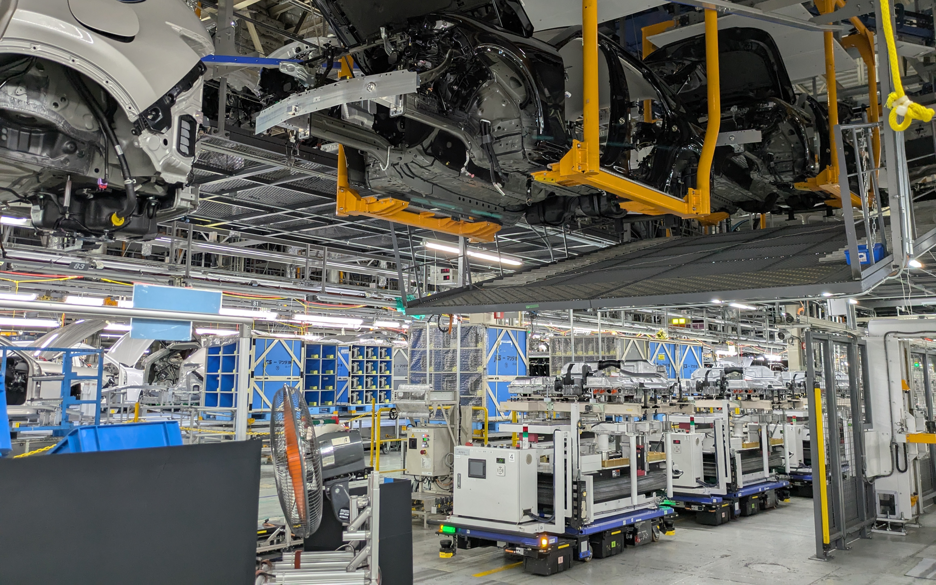 上部にあるハンガーの動きとリンクして、リチウムイオンバッテリを搭載したAGVが移動を開始。すべてコンピュータ制御されている