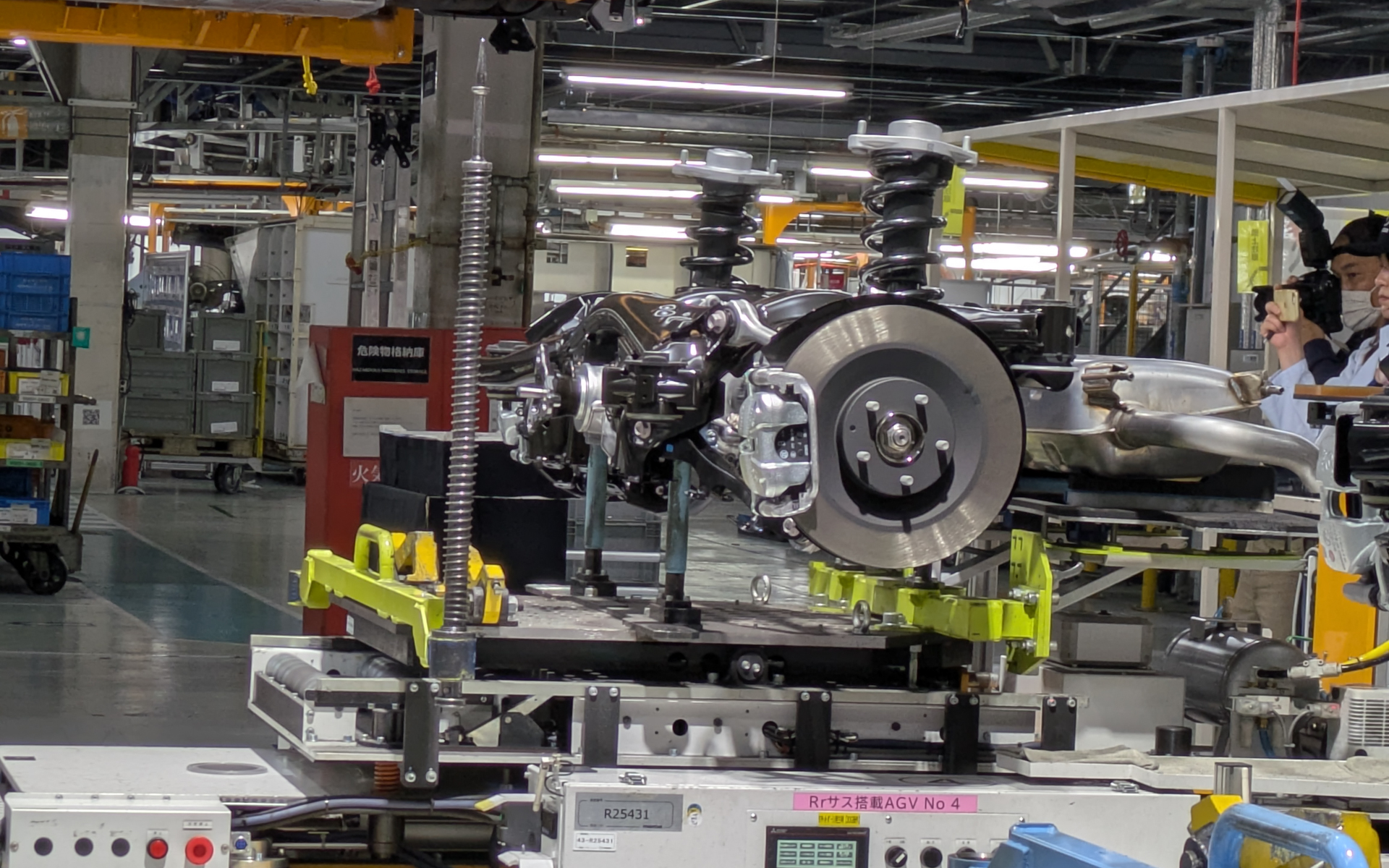 車種によって異なる取り付け部分については、位置決め具（水色や黄色の部品）の取り付け、取り外しのみで簡単に切り替え可能な設備にしてあり、同一工程での組み立てを可能としている