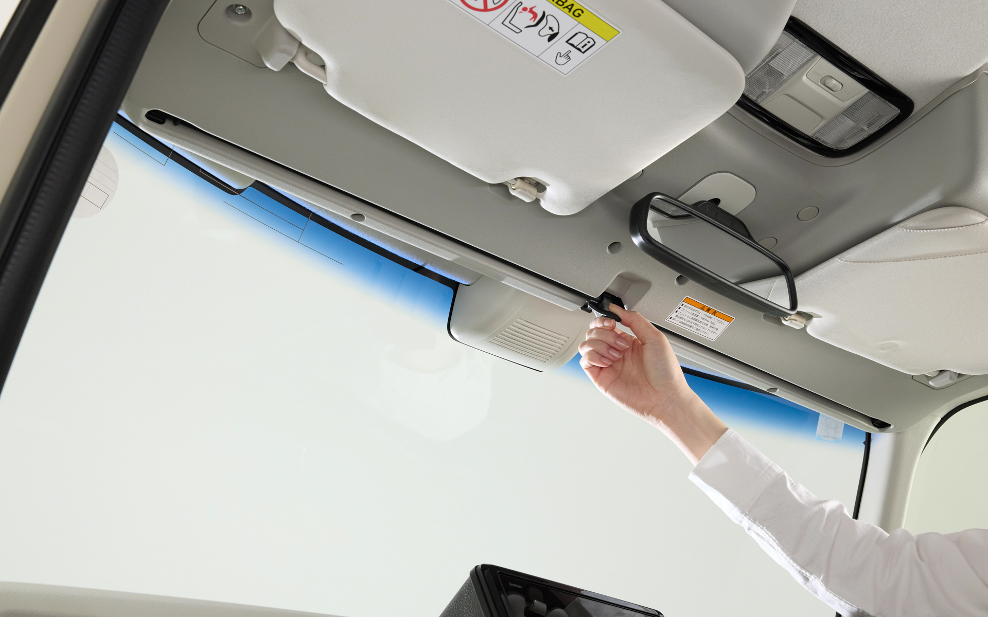 内蔵サンシェードはノブを片手でつまんで引き出し、ダッシュボード上のホルダーに掛けるだけの簡単操作