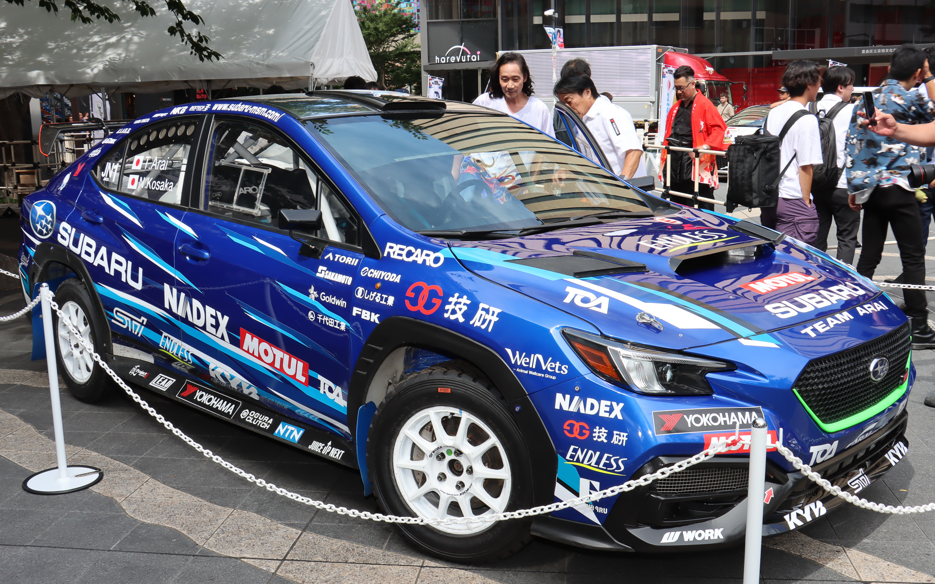 記事序盤のフォトセッションは発表会終了後に場所をとしま区民センターから隣接する中池袋公園に実施されたものだが、新井選手と三木さんは終了後もしばらく一緒に行動して、新井選手が三木さんに展示車などについて解説していた