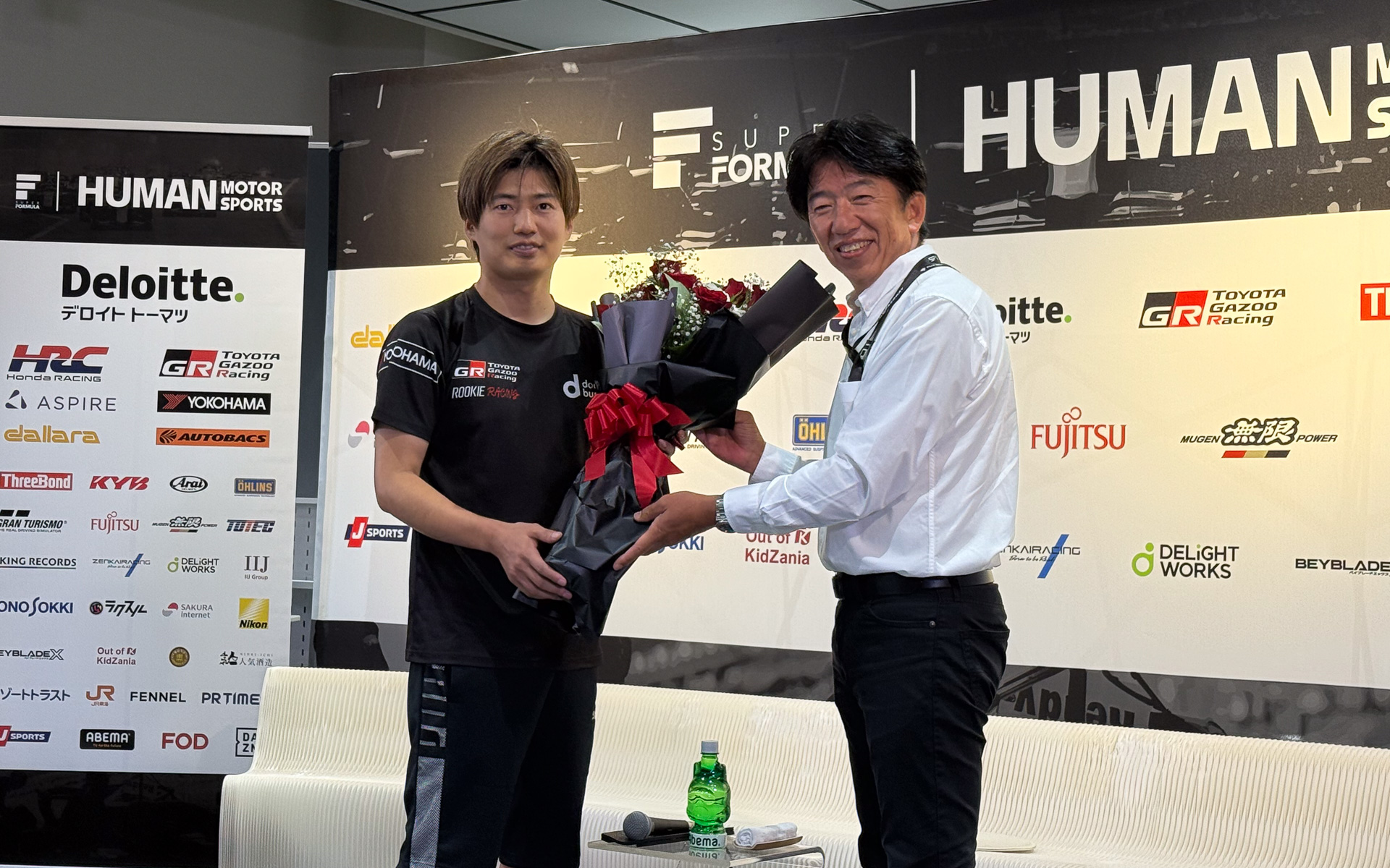 トップフォーミュラ参戦100戦を達成した大嶋和也選手（左）と、花束を贈呈するJRP（日本レースプロモーション）代表取締役社長 上野禎久氏（右）