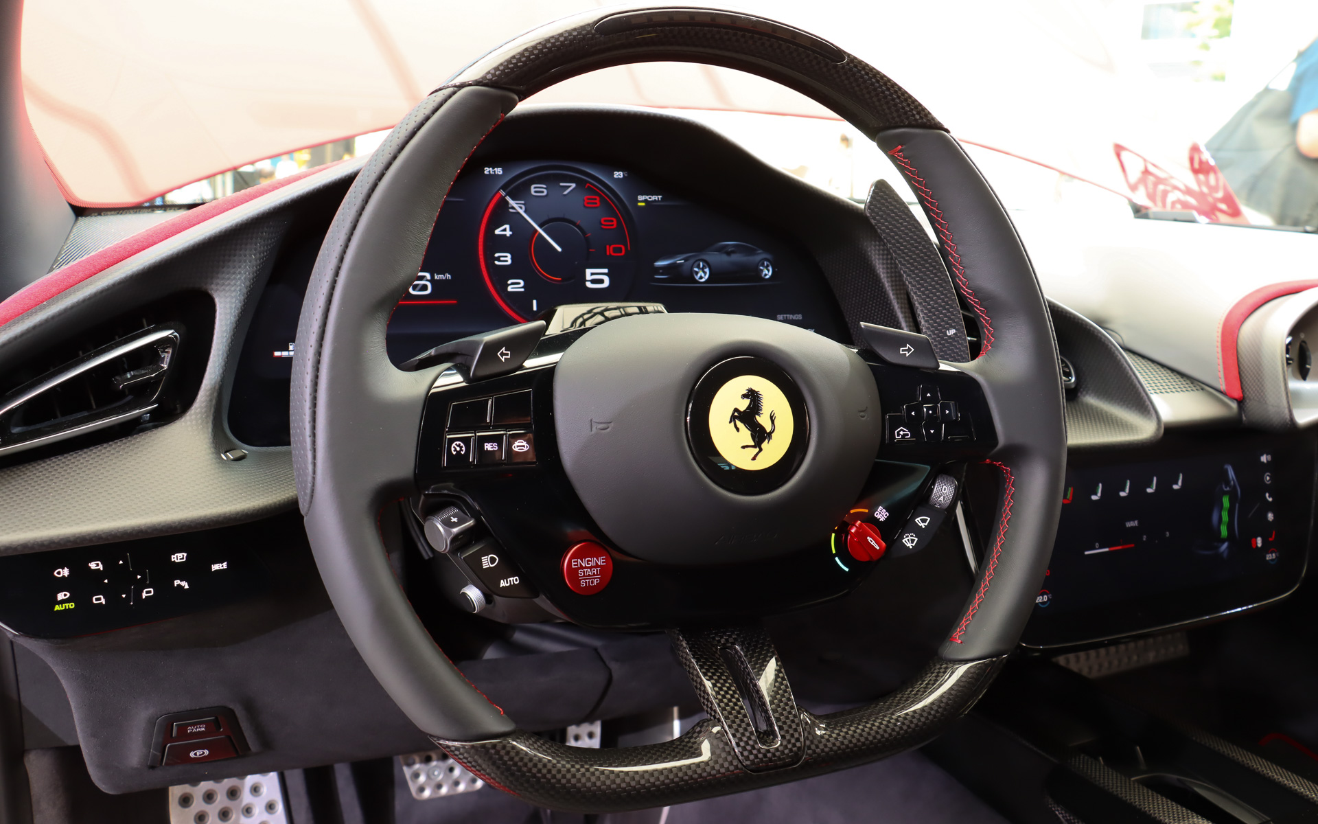 ステアリングには多彩な物理ボタンを備え、F1マシンを連想させるデザインとなっている。左下にあるエンジンのスタート/ストップボタンはアルミニウム製