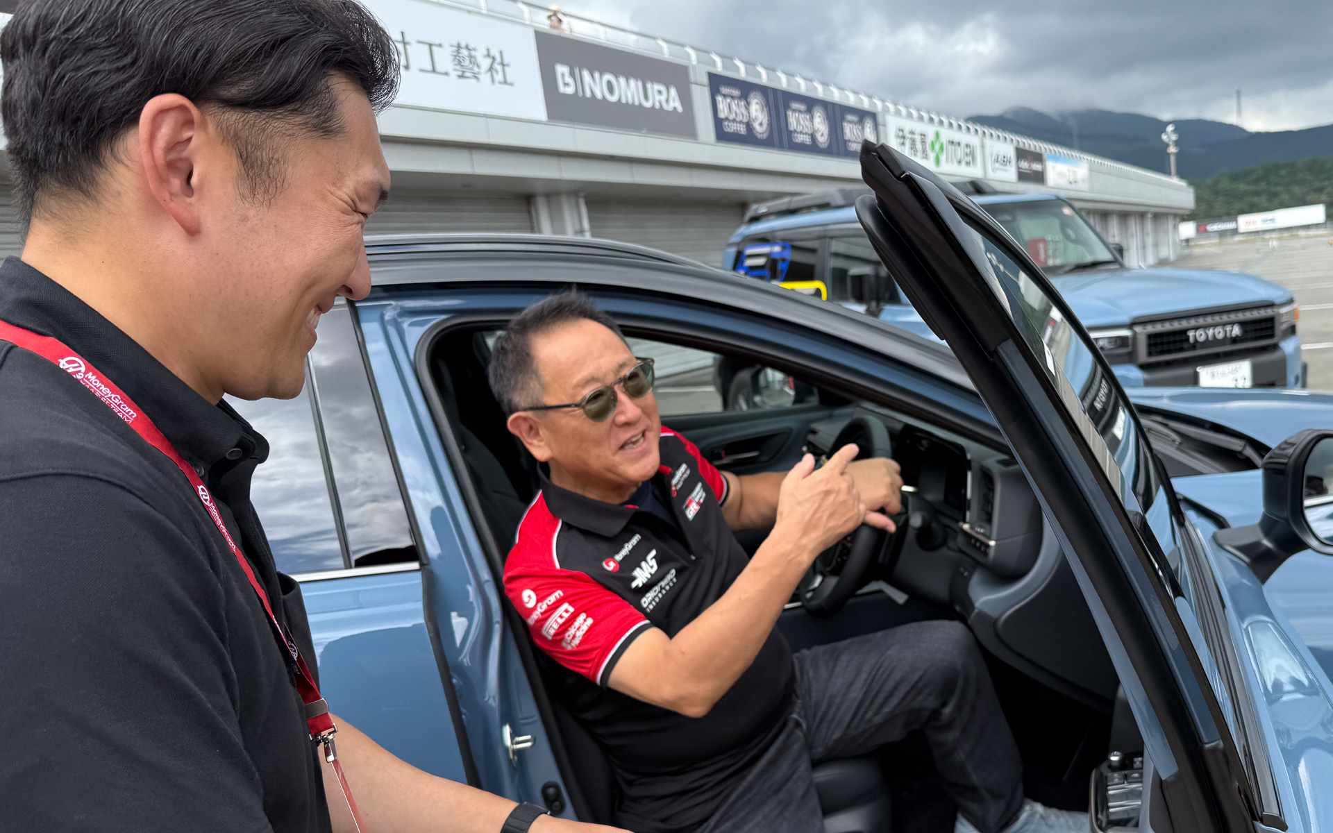 富士スピードウェイにハースF1シャツで登場したトヨタ自動車株式会社 代表取締役会長 豊田章男氏。カラーリングを終えた新車もあり、乗り込んで「新車のにおいがする！」とよろこんでいた