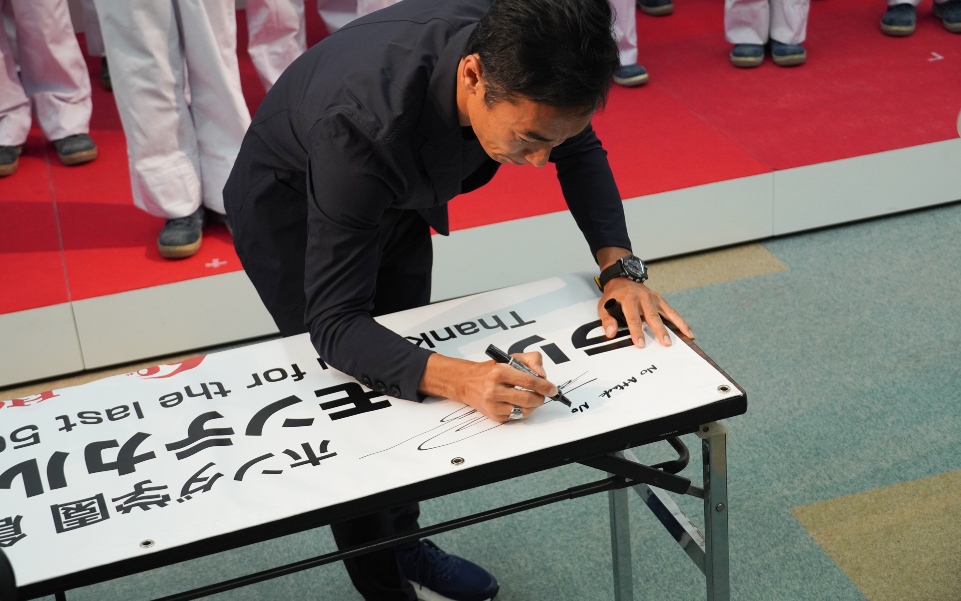 横断幕にサインとメッセージを書く佐藤琢磨選手