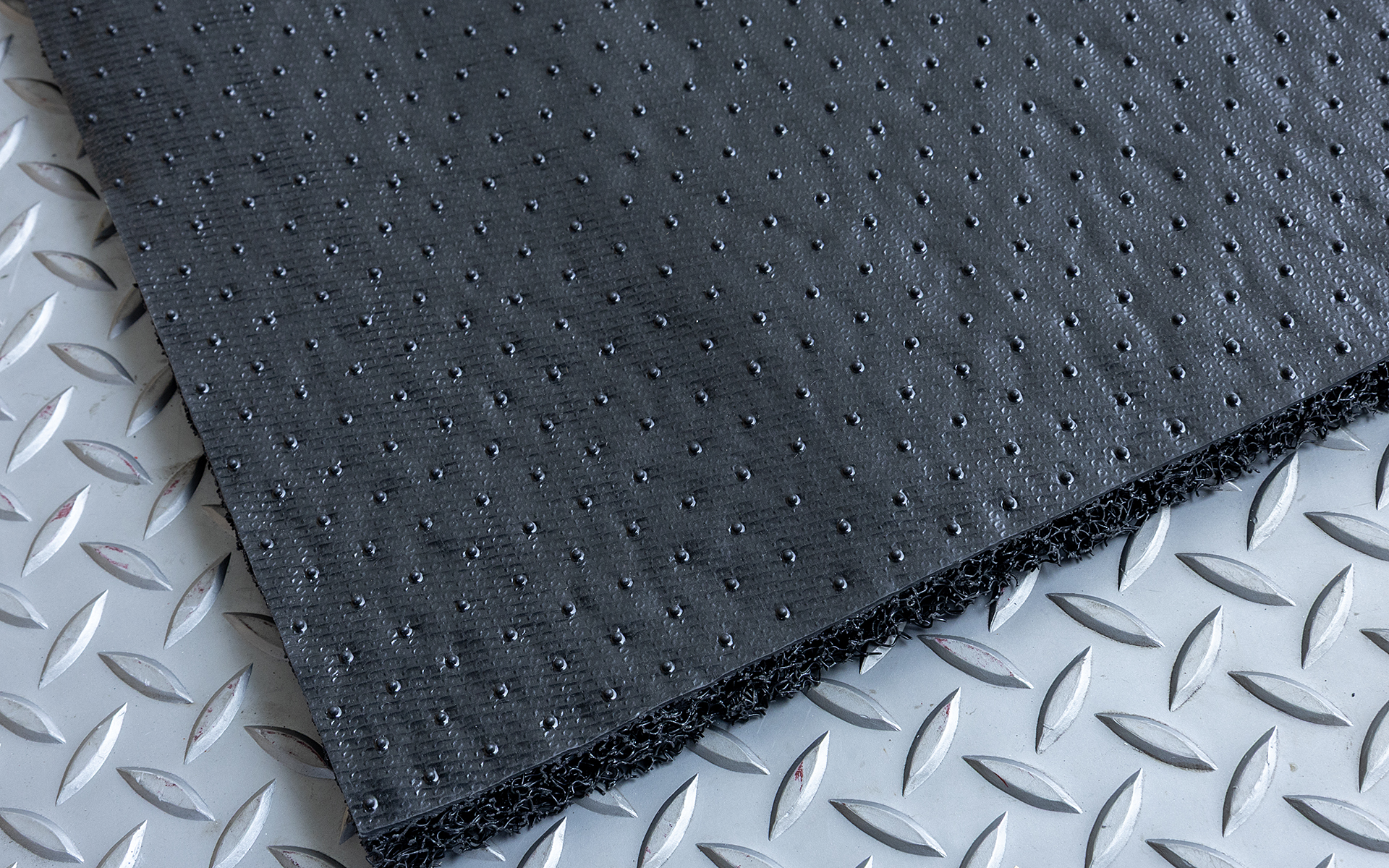 裏面には遮音効果のある高密度な素材を使用。純正フロアマットに載せたときに滑りにくくするために突起状の加工もされている