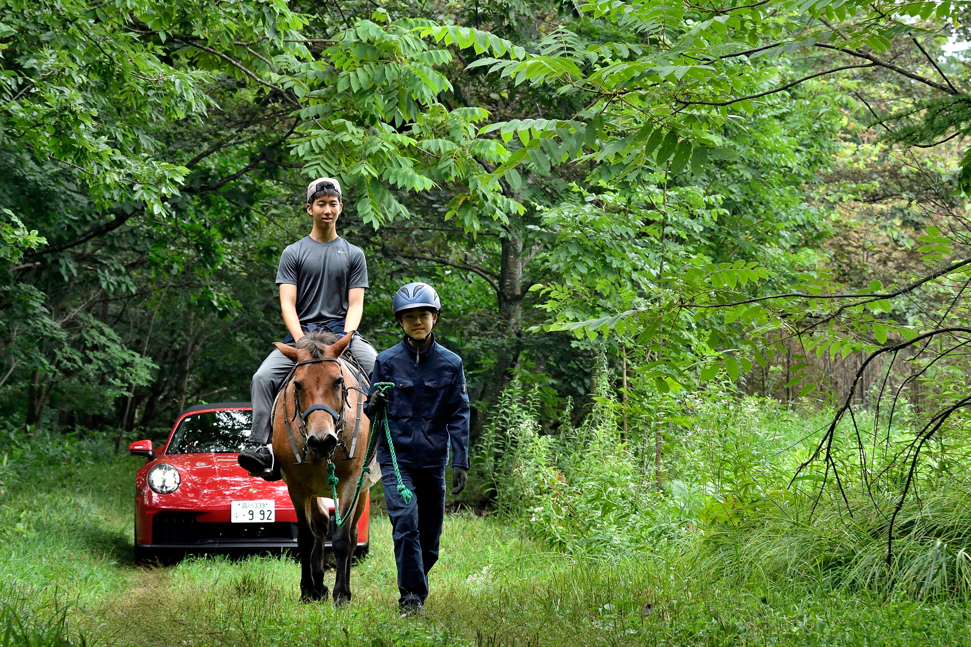 捕まえた馬とともにトレーラーを装着したポルシェトラクター、最新の911が連なり森へ入っていく