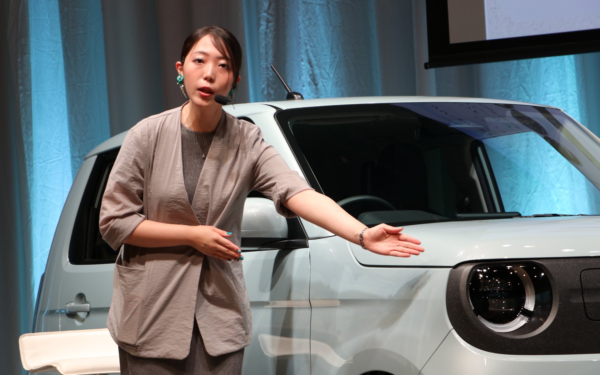 株式会社本田技術研究所　N-ONE e: 開発デザイナー 古小路実和（こしょうじ みわ）氏。フロントグリルにサステナブル素材を活用していることを説明してくれた