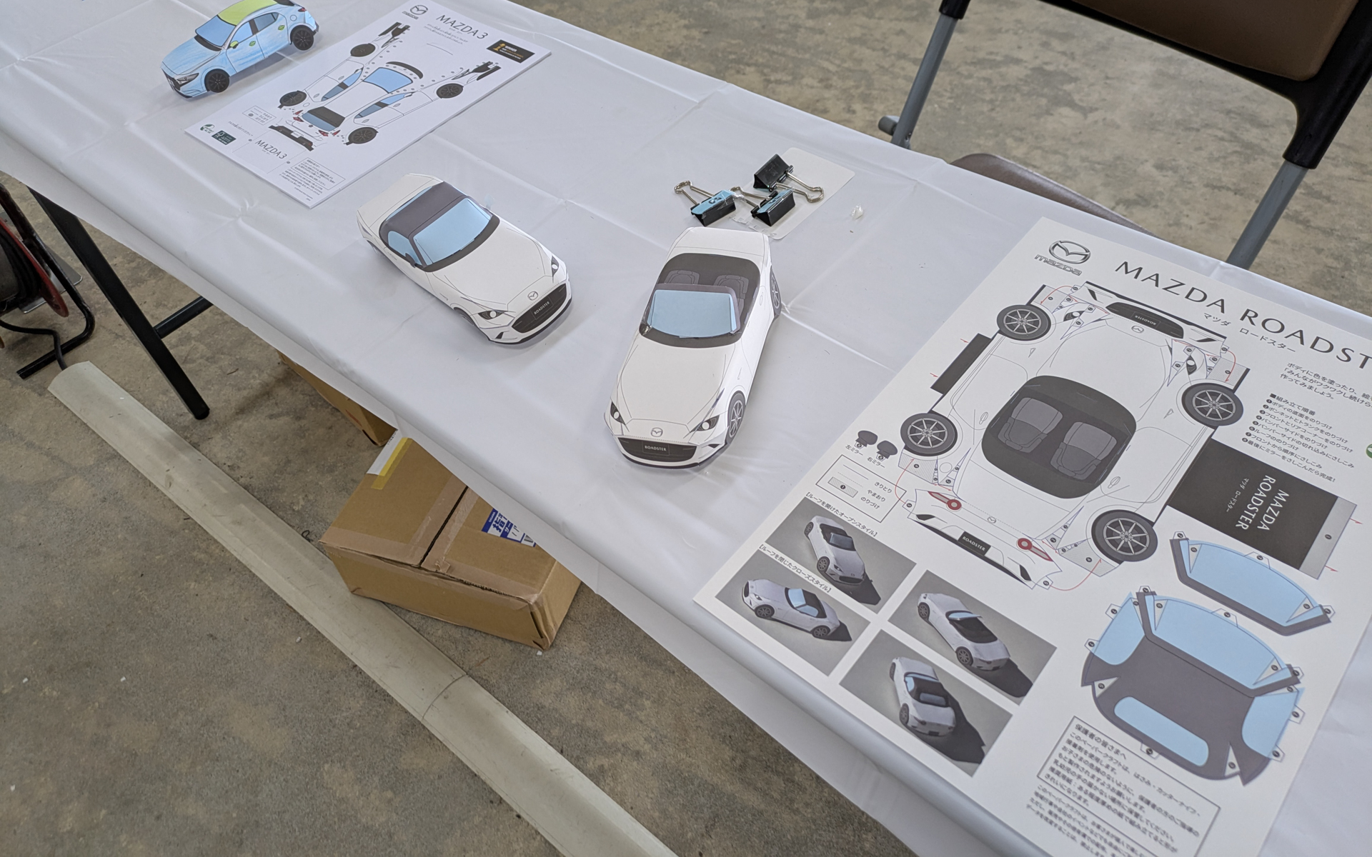 マツダ車のペーパークラフトを組み立て、色を塗ることができるコーナー。オリジナル缶バッヂ制作も大人気で、昼前には完売していた