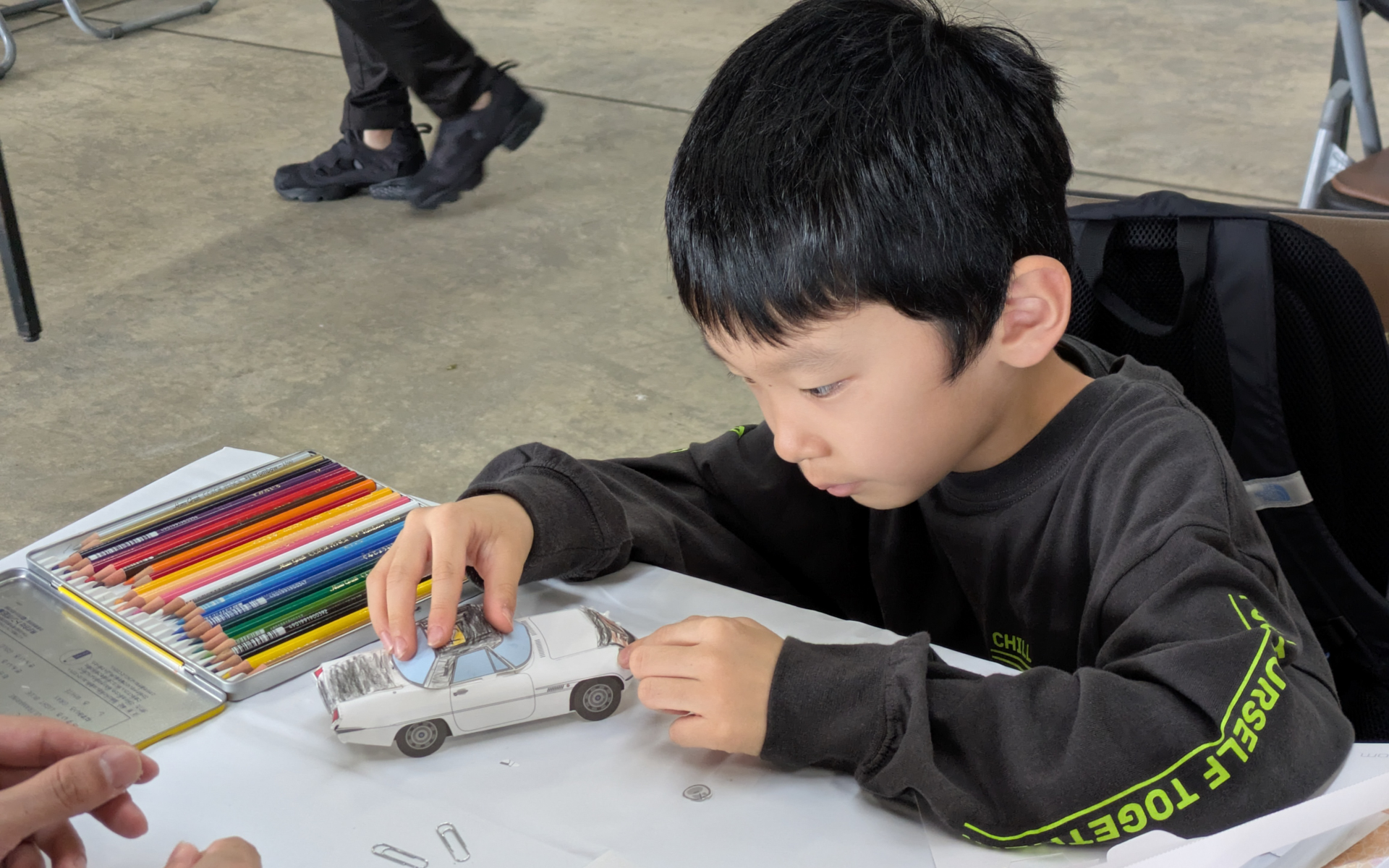 マツダ車のペーパークラフトを組み立て、色を塗ることができるコーナー。オリジナル缶バッヂ制作も大人気で、昼前には完売していた