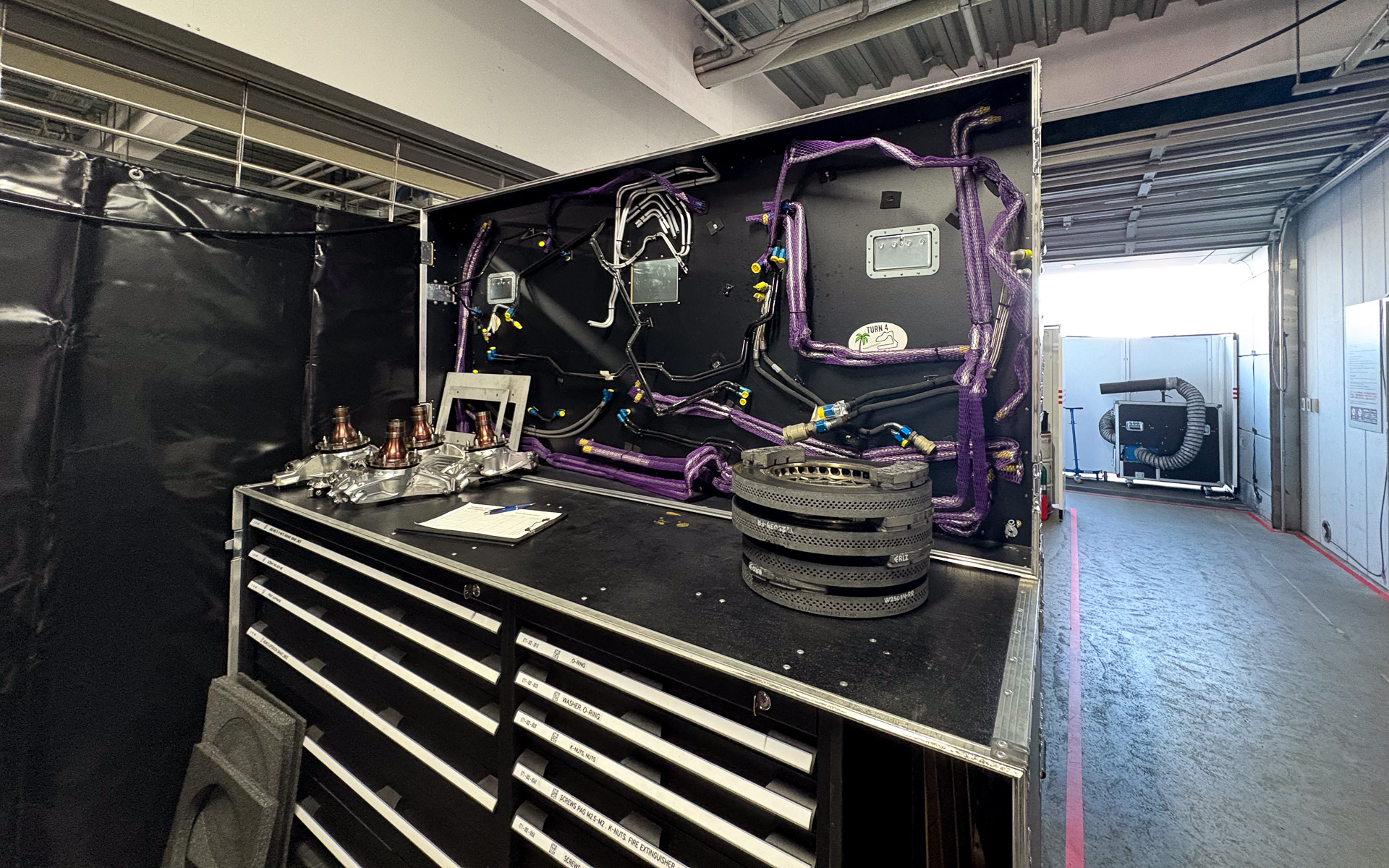 工具箱の上に置かれたハブとカーボンブレーキ。ハブはアルミのインゴットをマシニングしたものか？　とにかくゴツくて、見た目がきれい。カーボン製のブレーキローターは、その分厚さと外周に開けられた通気口が独特。恐らく内部はベンチレーションになっているのだろう、C/Cコンポジット製法だからこそできるデザインだ