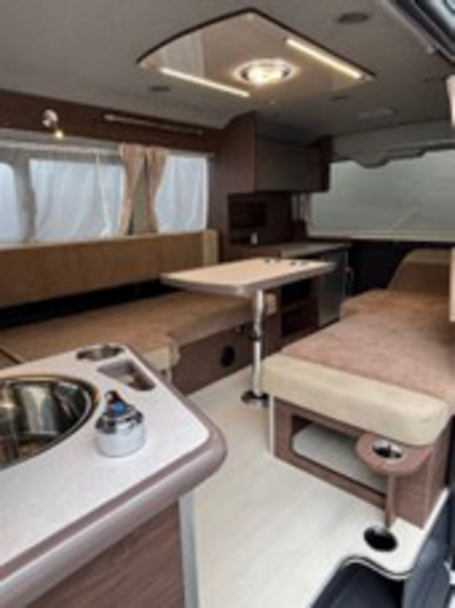 後部には家庭用エアコンと電子レンジを標準装備。ベットスペースは、対角線上に寝る独特な配置し、書斎としても使えるデスクも完備する