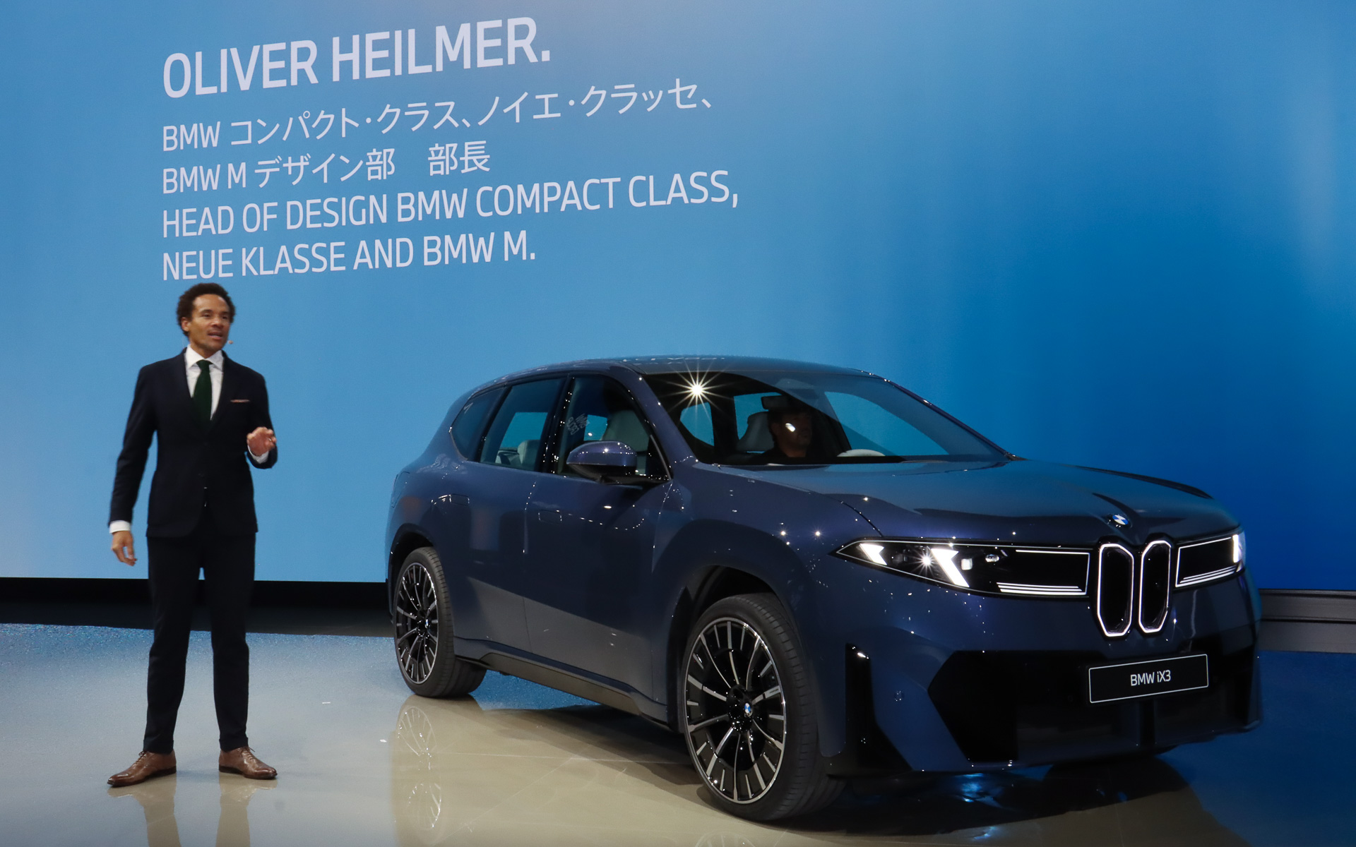プレスブリーフィング中にステージ上に姿を現わしてアジア初公開された新型「iX3」とBMW コンパクトクラス ノイエ・クラッセ BMW M デザイン部 部長 オリバー・ハイルマー氏