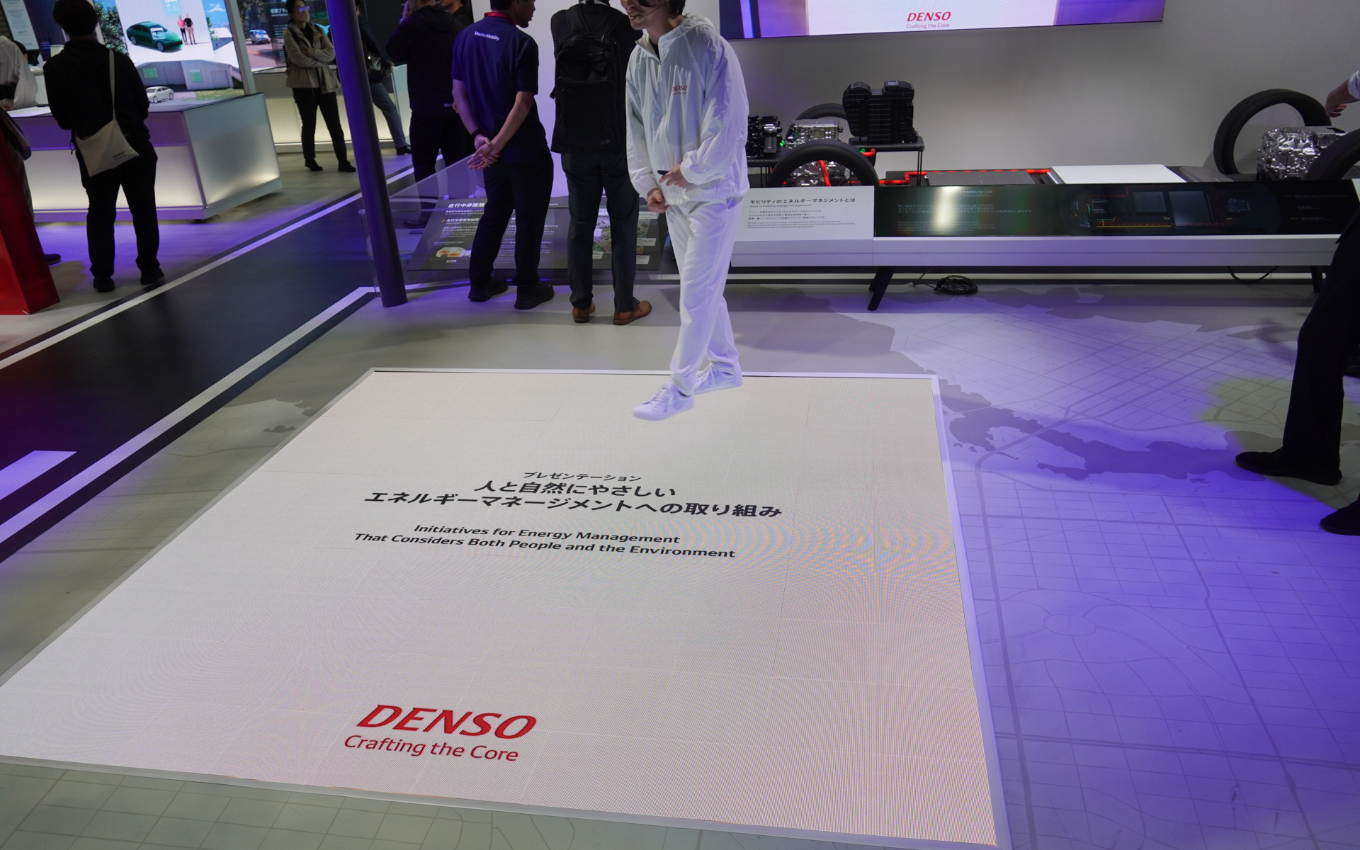 エネルギーマネジメントをプレゼンターが床面のスクリーンを使って説明する